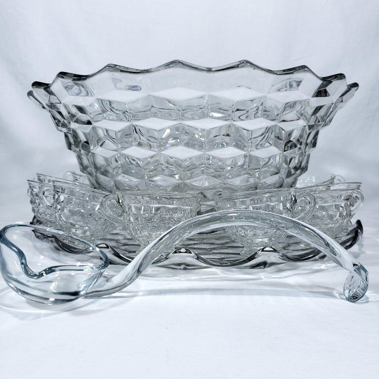 American Clear (Stem 2056) Pressed Glass by Fostoria
Crafted in United States
Circa: 1915's
Dimensions: 
1 - Bowl Width: 18 1/2 in Height: 8 in
1- Underplate Width: 19 1/4 in
12 - Cup Height: 2 1/2 in Width: 3 3/4 in  
1 - Glass Punch Ladle Length: