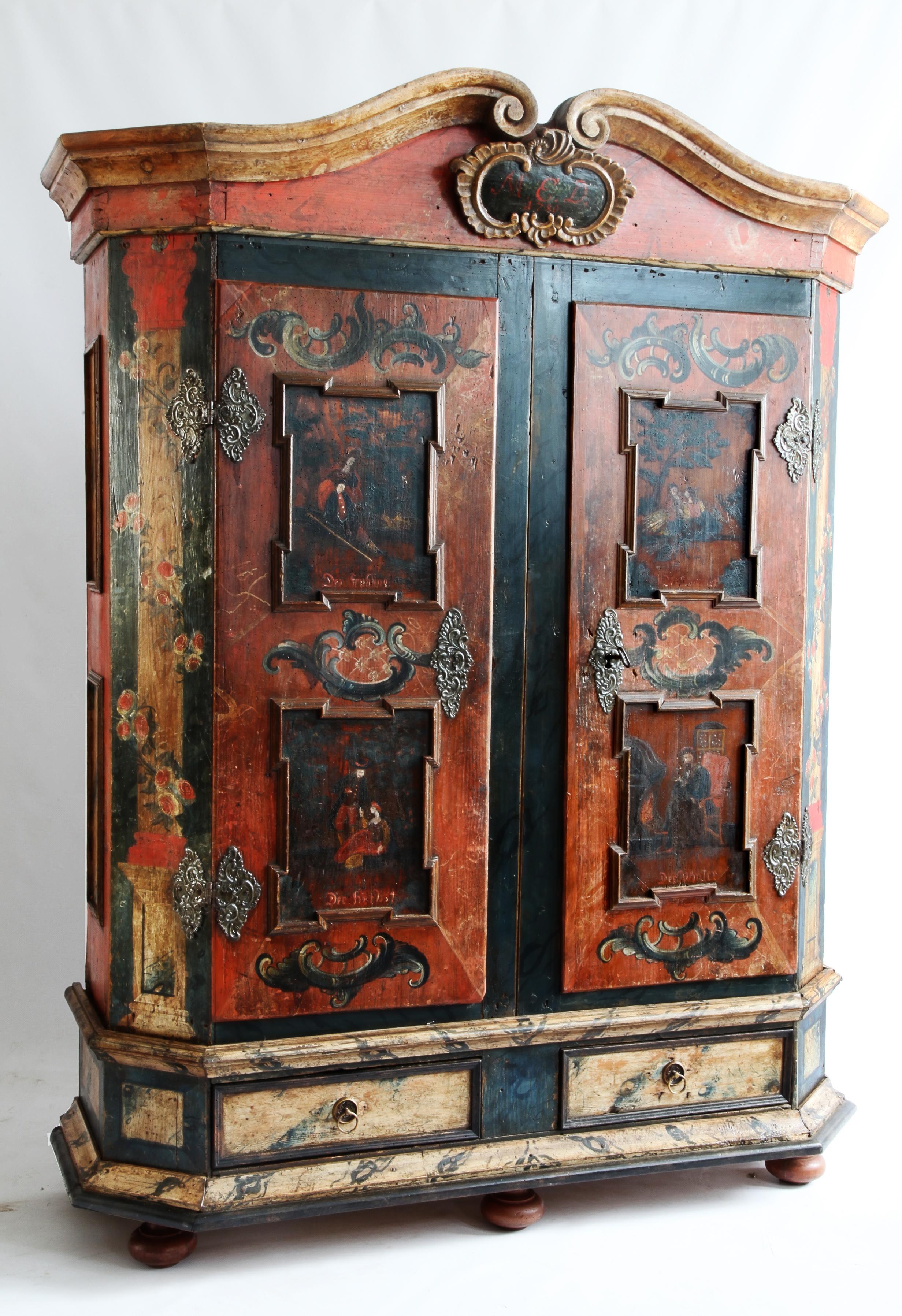 A colorful 18 century armoire from Bolanzo, N. Italy painted in the Tyrolean style dated 1780 in a primary deep warm red ochre with prussian blue and cream used for the decoration of marbling, roses and Rococo stylized flourishes. Features central