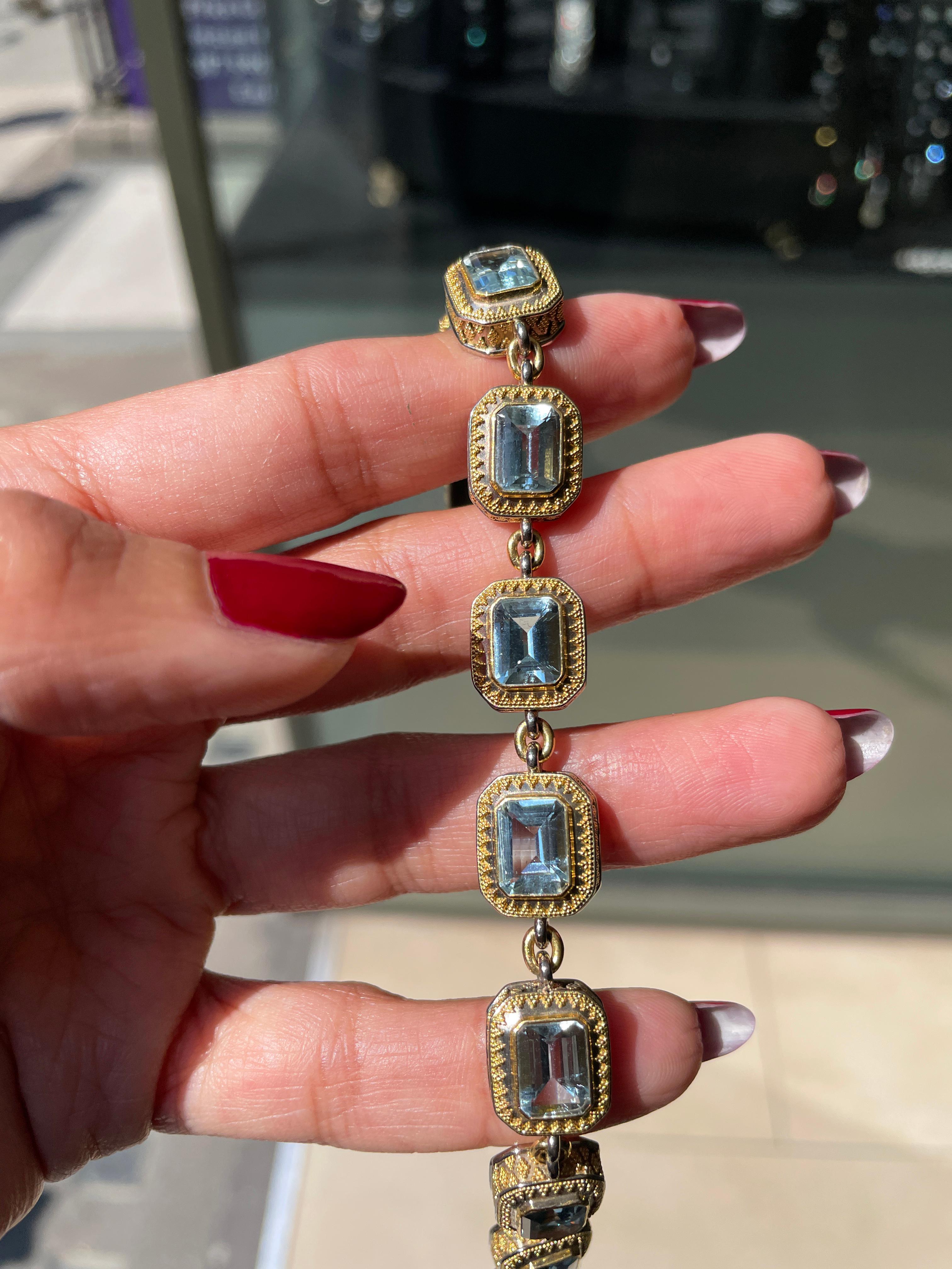 Modern link gold bracelet set with ten emerald cut aquamarines weighing approximately 1.25 carat - 1.50 carat each. The stones are individually mounted in solid decorative rub-over open back collets and all connected with a yellow gold link. Stamped