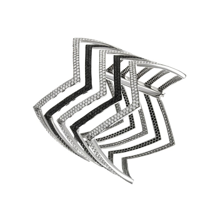 Constrasting black and white diamonds are the theme of this elegant and timeless cuff. The chevron design is delicately carved out of 18k white gold giving the piece a modern edge. Over 17 carats of alternating black and white diamonds are pave'd