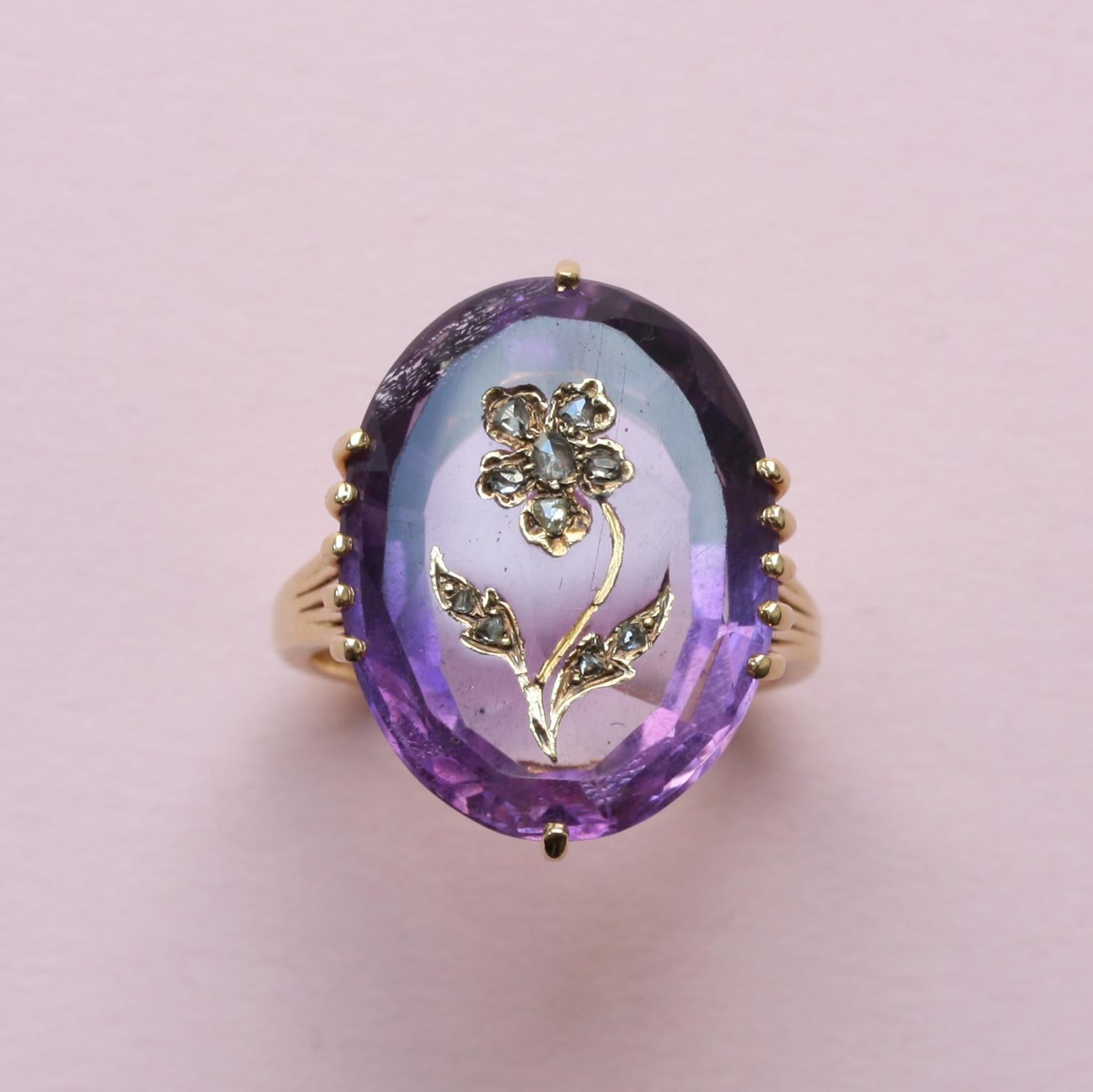 An 18 carat gold ring set with a large oval facetted amethyst that is decorated with a flower or pansy encrusted in gold with rose cut diamonds, France circa 1910.