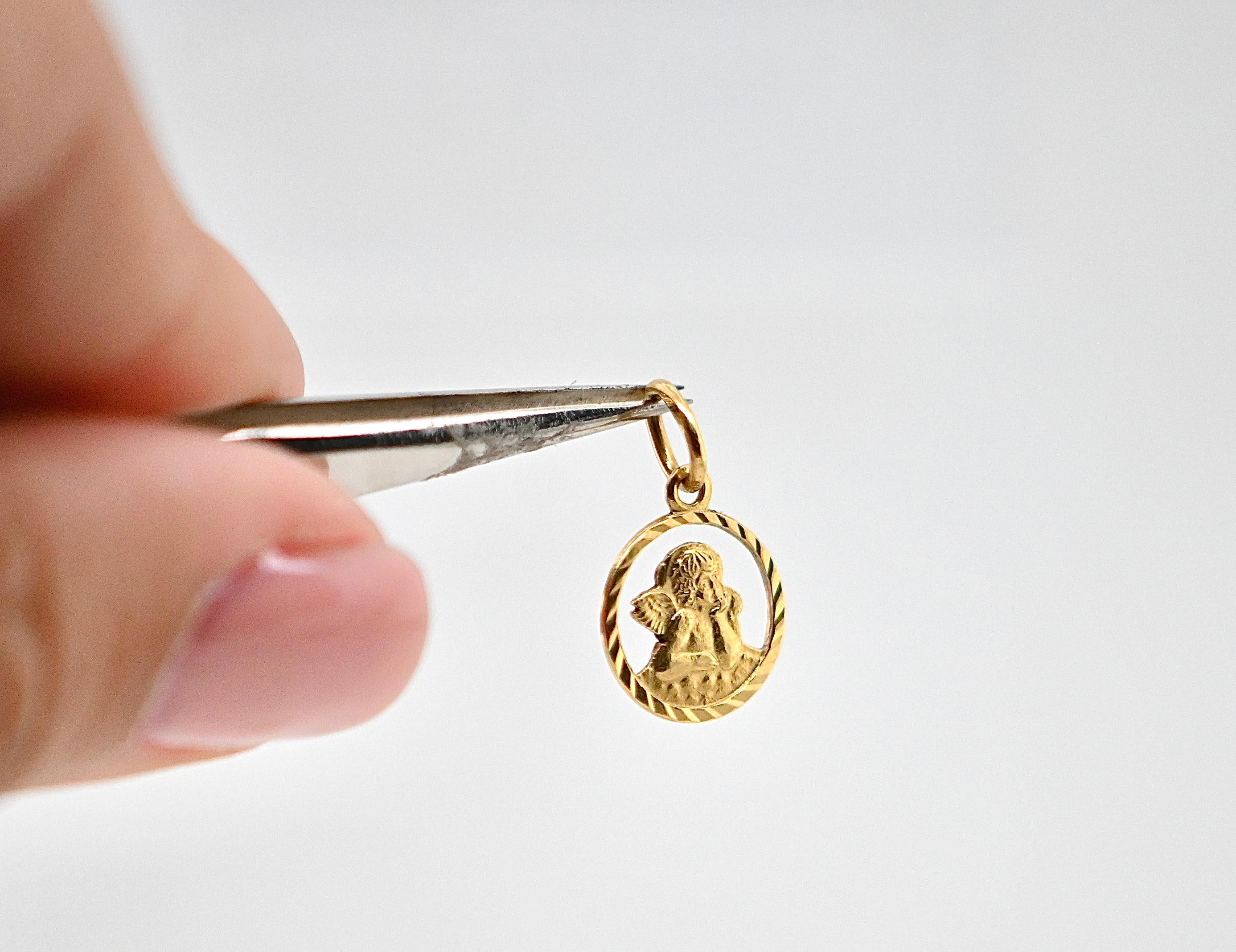 Questo magnifico ciondolo in oro 18 carati, che misura 1 cm di diametro e pesa 0,6 g, è un pezzo delicato e raffinato. Raffigura un angelo pacifico, che appoggia la testa sulla mano e guarda il cielo con un'espressione di serenità e contemplazione.