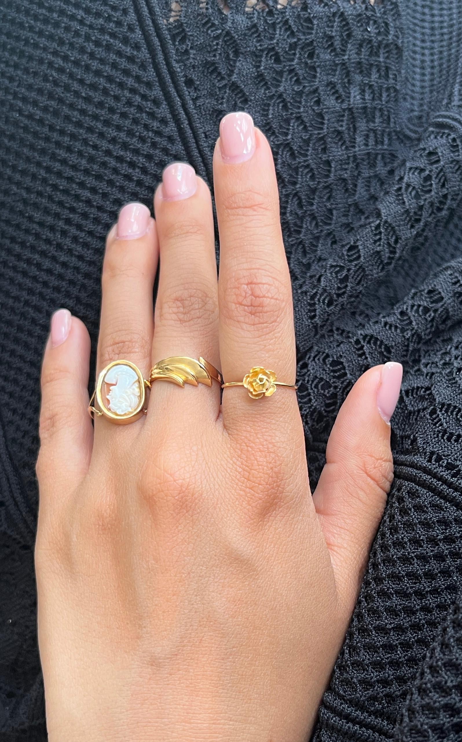 This antique 18-carat gold ring features an oval cameo depicting an elegant woman. The woman, with her hair knotted at the top, smiles softly and wears a delicate pearl necklace, adding a touch of timeless charm and grace.

A master hallmark