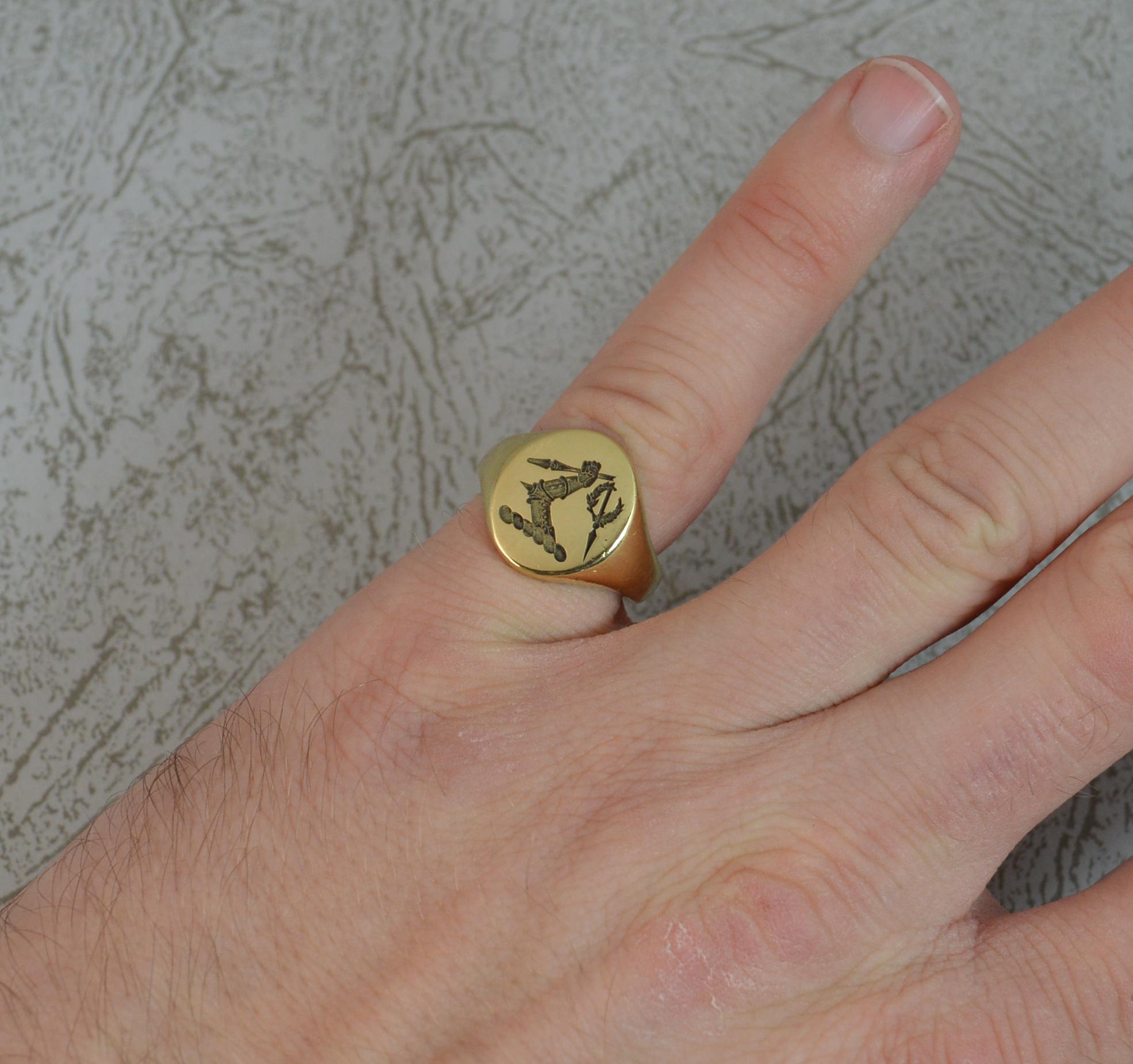 A superb unisex seal signet ring.
Solid 18 carat yellow gold example.
Designed with a family crest which depicts an arm in full armour holding a spear which has broken in two and the loose section having a wreath around it.
12mm x 15mm head