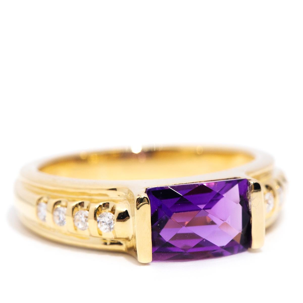 Lovingly forged in 18 carat yellow gold, this gorgeous vintage ring features four sparkling round brilliant diamonds in the band and holds an enchanting checkerboard cut deep purple amethyst. This captivating adornment is named The Lavender Ring.