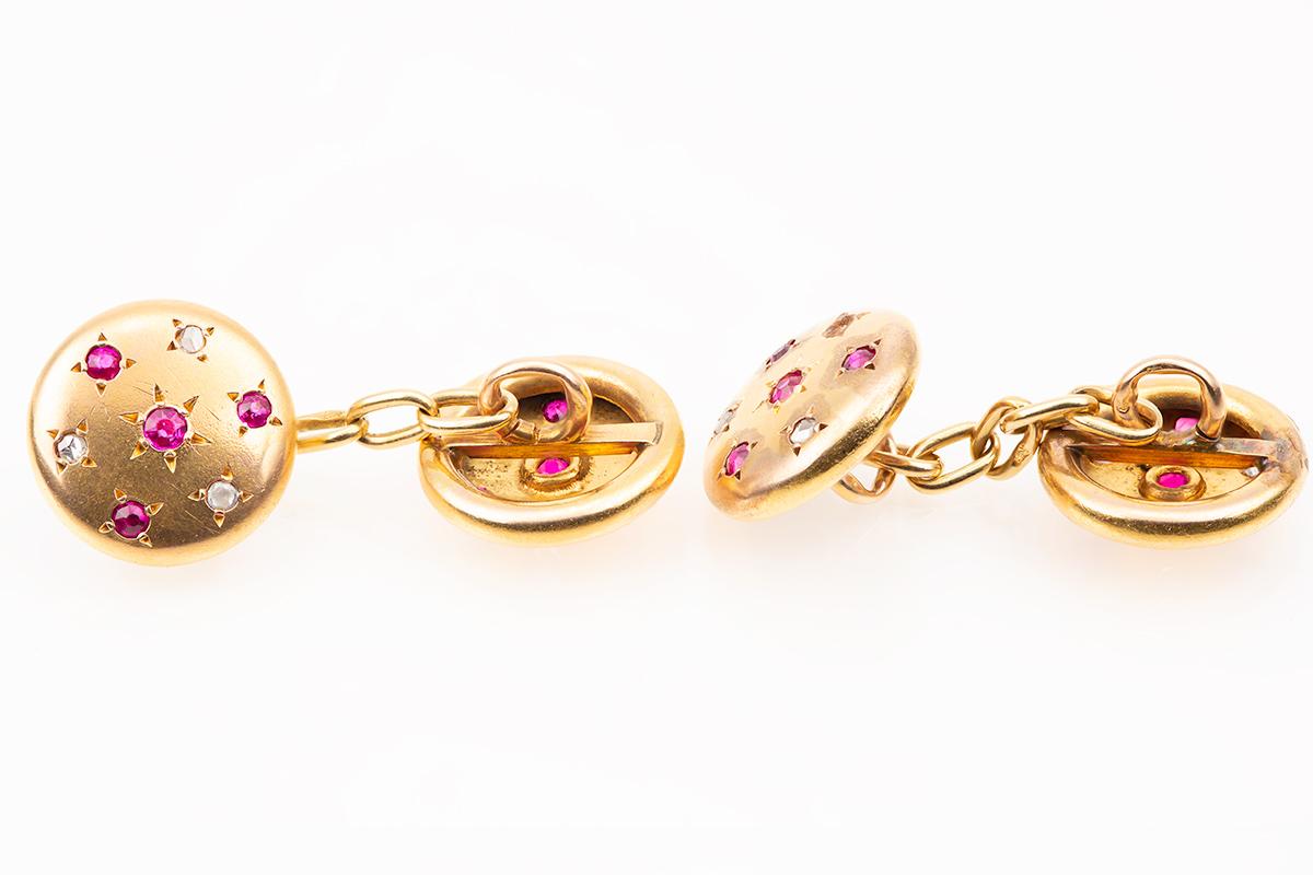 A pair of antique double sided cufflinks in 18 carat yellow gold. Circular in shape and set with four very pretty Burma rubies and three rose cut diamonds in a star-like setting. The gold has a particularly soft patina. Chain link connections with
