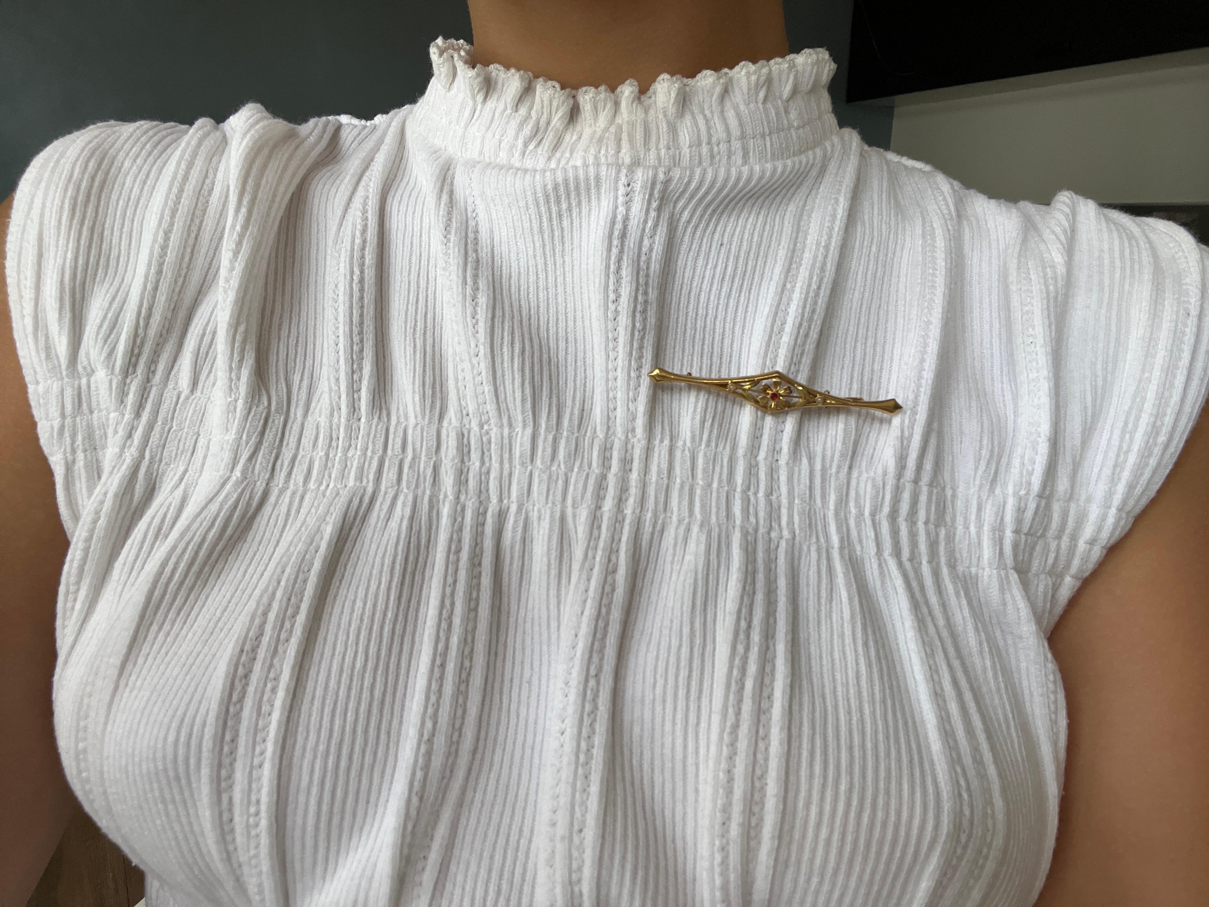 Discover this magnificent brooch in 18-carat gold, certified by a French master hallmark. Art deco in style, this elegant, timeless piece is perfect for adding a touch of sophistication to your outfit.

At the center of the brooch is a delicate