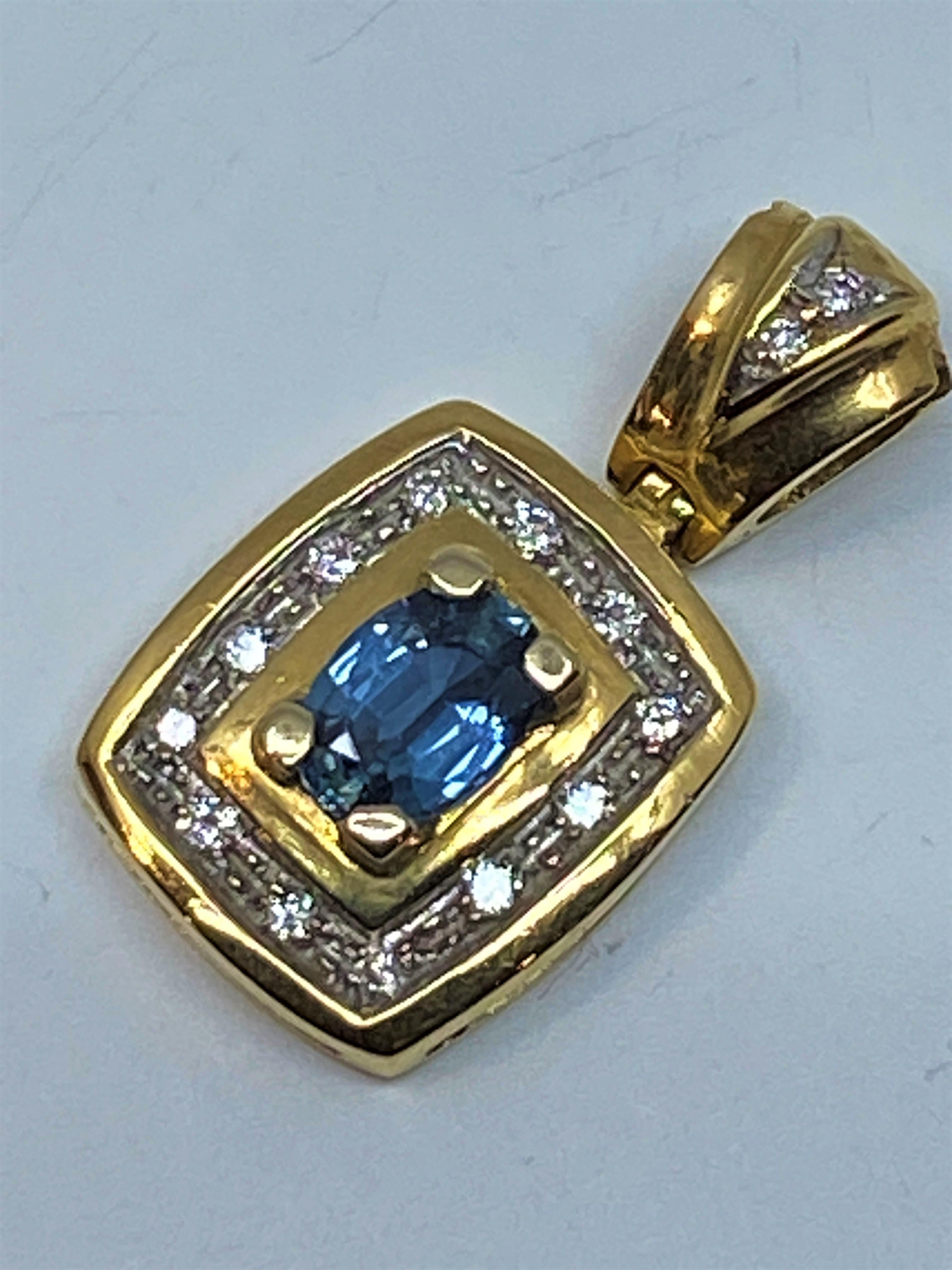 Joli pendentif en or 18 carats orné au centre d’un saphir entouré de 14 diamants. La bélière mobile est sertie de 2 diamants dans un motif triangulaire. Le saphir est serti par 4 griffes et les diamants sont en serti grains, l’ensemble dans un serti
