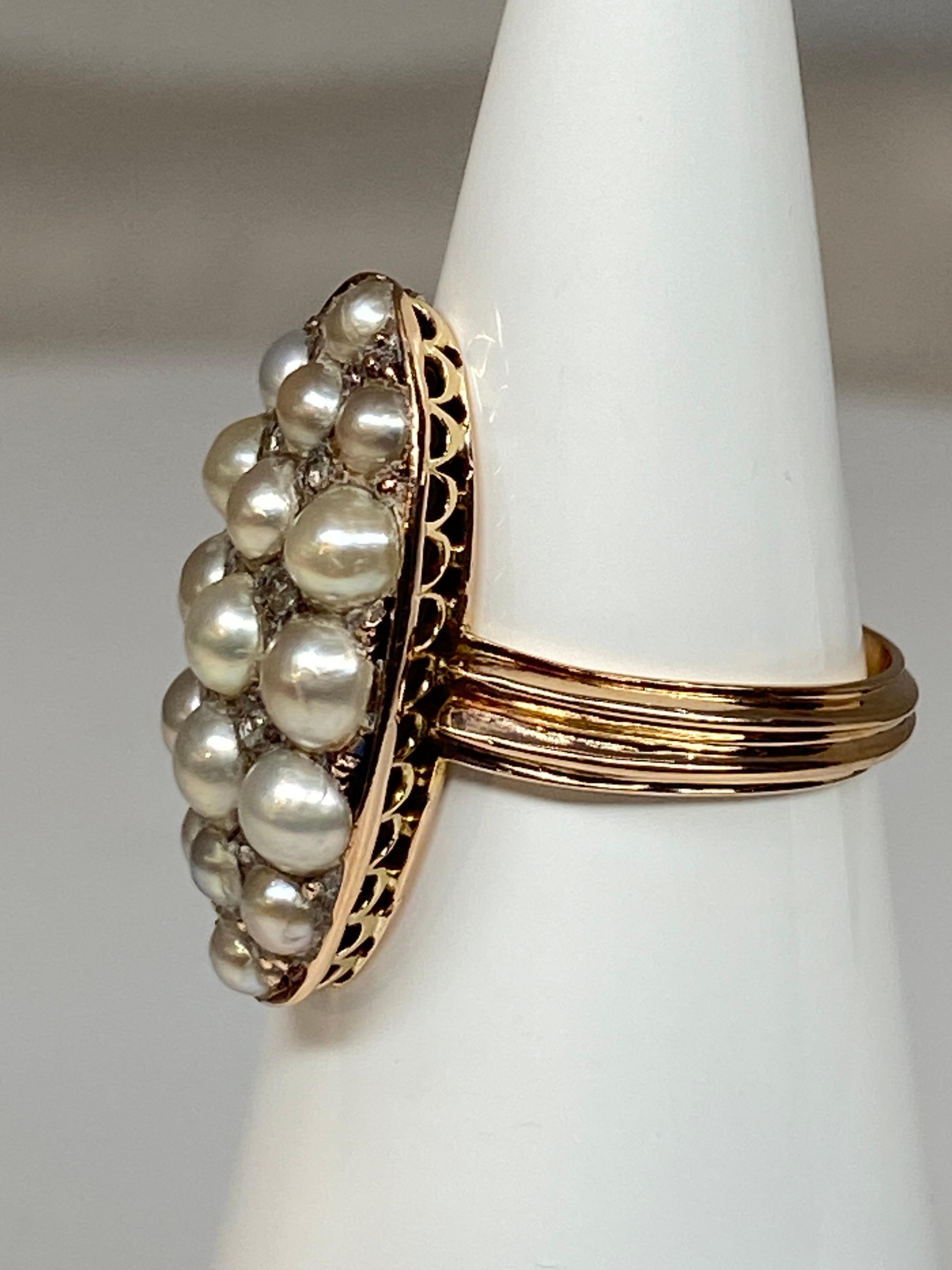 Superbe bague en or 18 carats de forme marquise sertie de 17 demi perles fines et de 8 diamants taillés en rose. Le panier est très finement ajouré, l’anneau est rehaussé de deux lignes d’or en relief. C’est une charmante bague très représentative