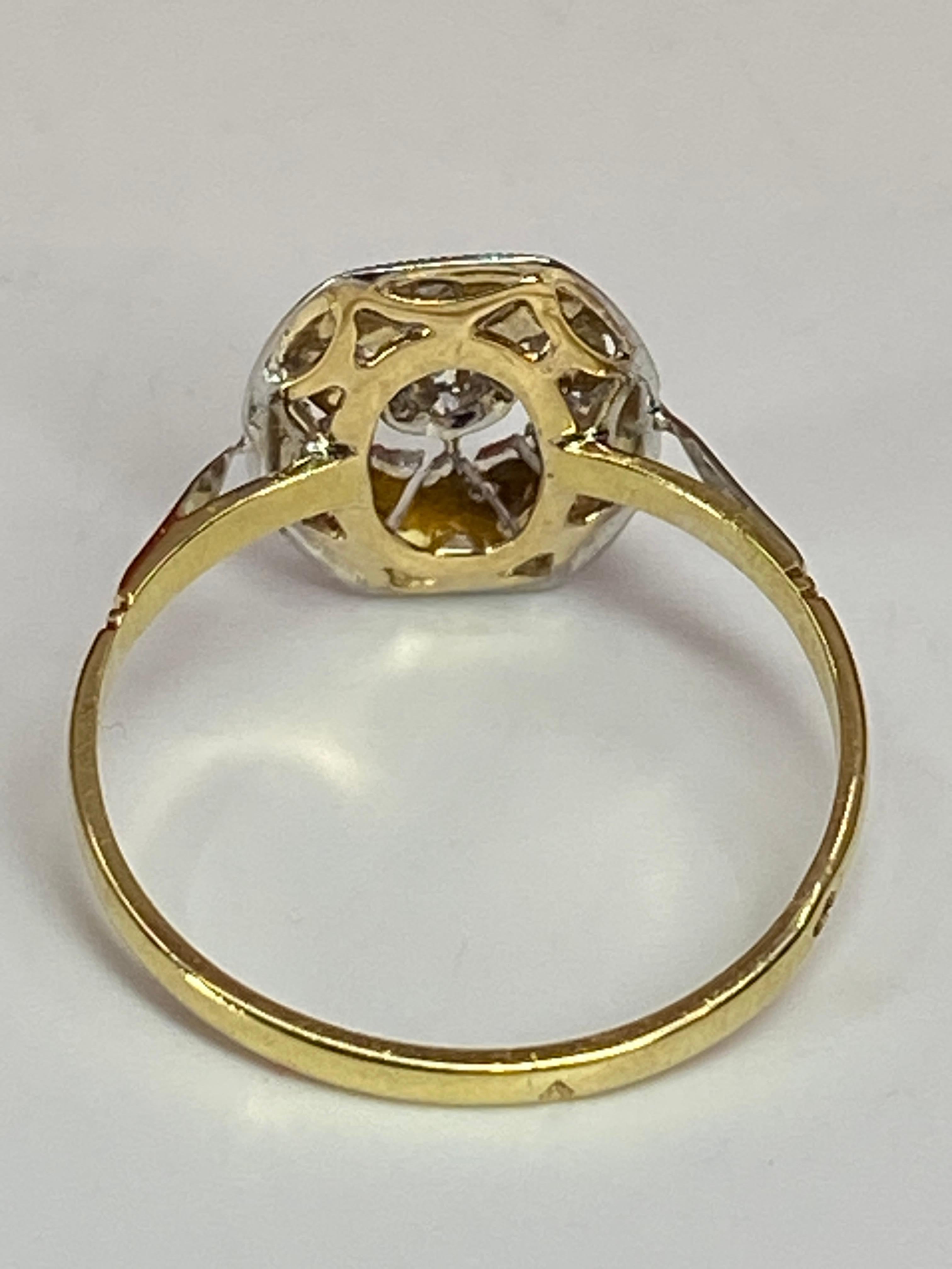 Cette charmante bague est en or jaune et or blanc 18 carats. Elle est ornée au centre d’un diamant de taille brillant pesant 0.05 carat environ. Il est en serti grains dans une petite collerette située au centre d’un plateau à décor géométrique