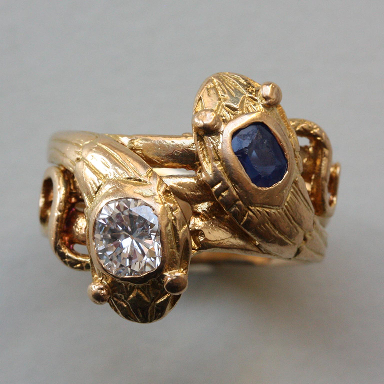 An 18 carat gold with two intertwined snakes their heads set with an old cut diamond (app. 0.45 carats) and a smaller cushion cut sapphire (app. 043 carats), master mark EA with a dolphin in between, circa 1910, France.

weight: 6.55 gram
width: 6 -