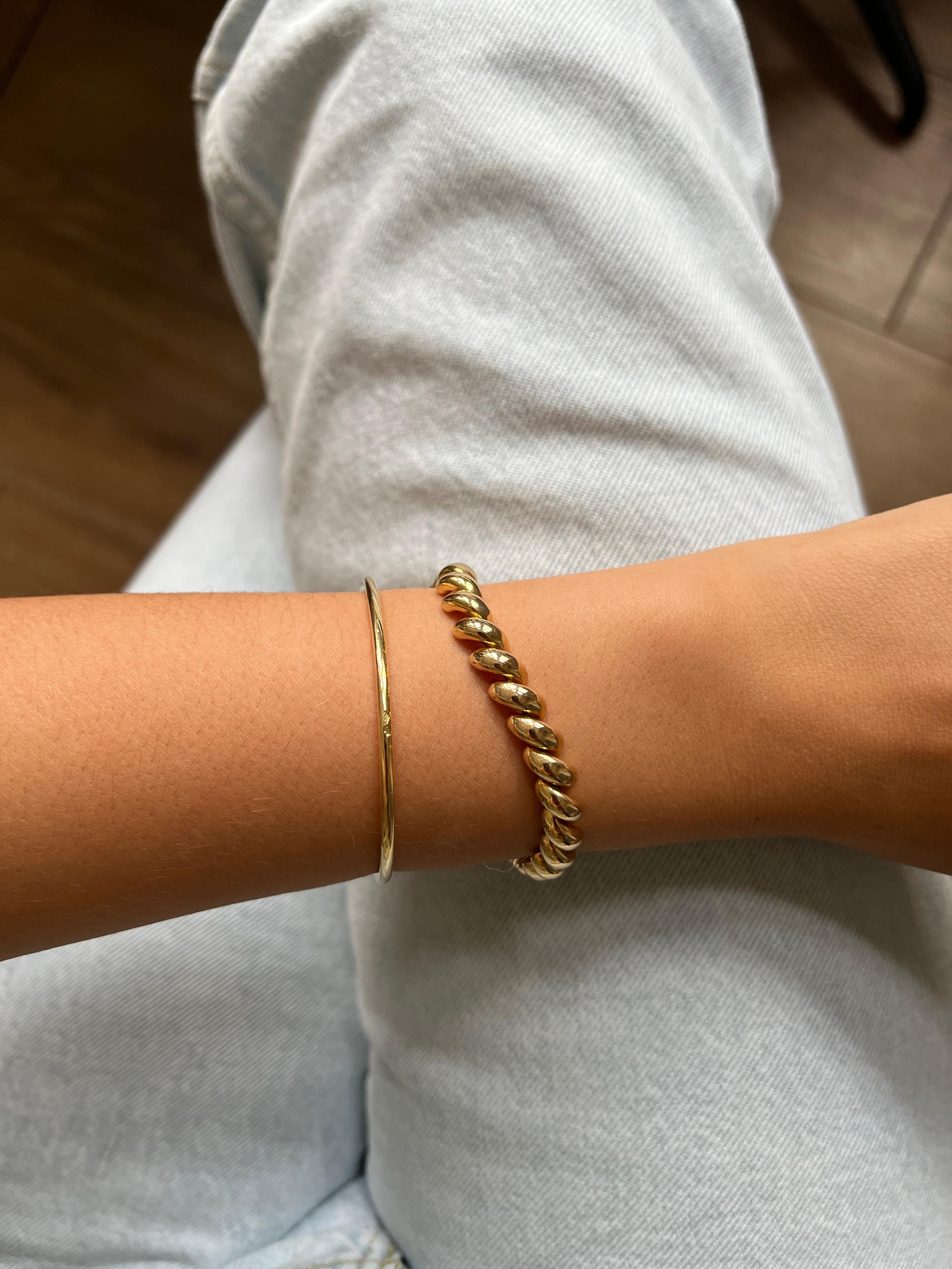 Ce bracelet en or 18 carats est une pièce élégante et raffinée, mesurant 18,5 cm de longueur et 0,7 cm de largeur. Il se distingue par ses maillons qui créent un effet de spirale, ajoutant une touche unique et sophistiquée à l'ensemble.

Le crochet