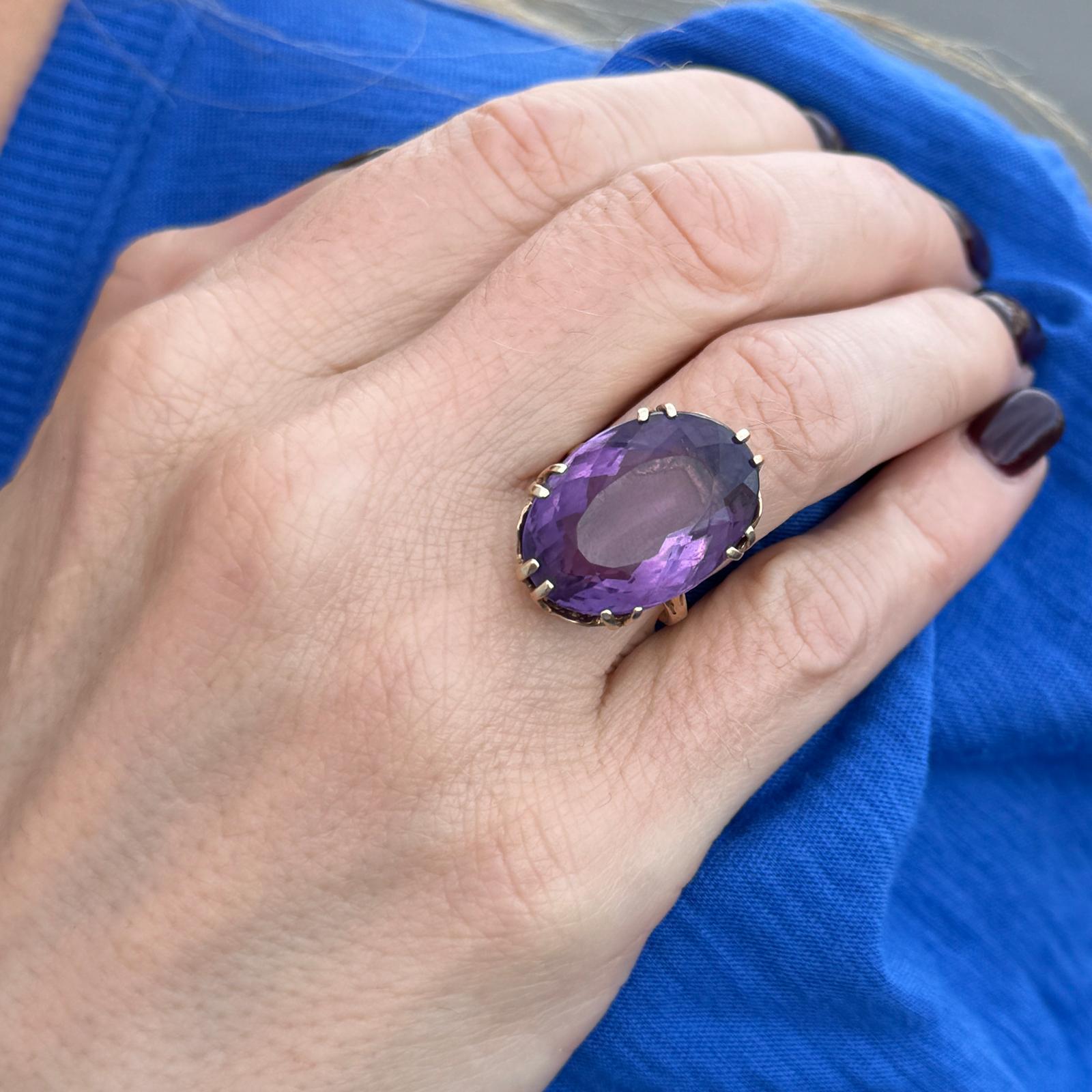 Vintage oval amethyst estate ring handcrafted in 14 karat yellow gold. The ring features an oval faceted amethyst gemstone weighing approximately 18 carats (by measurements) set in a beautifully crafted vintage mounting. The ring is currently size