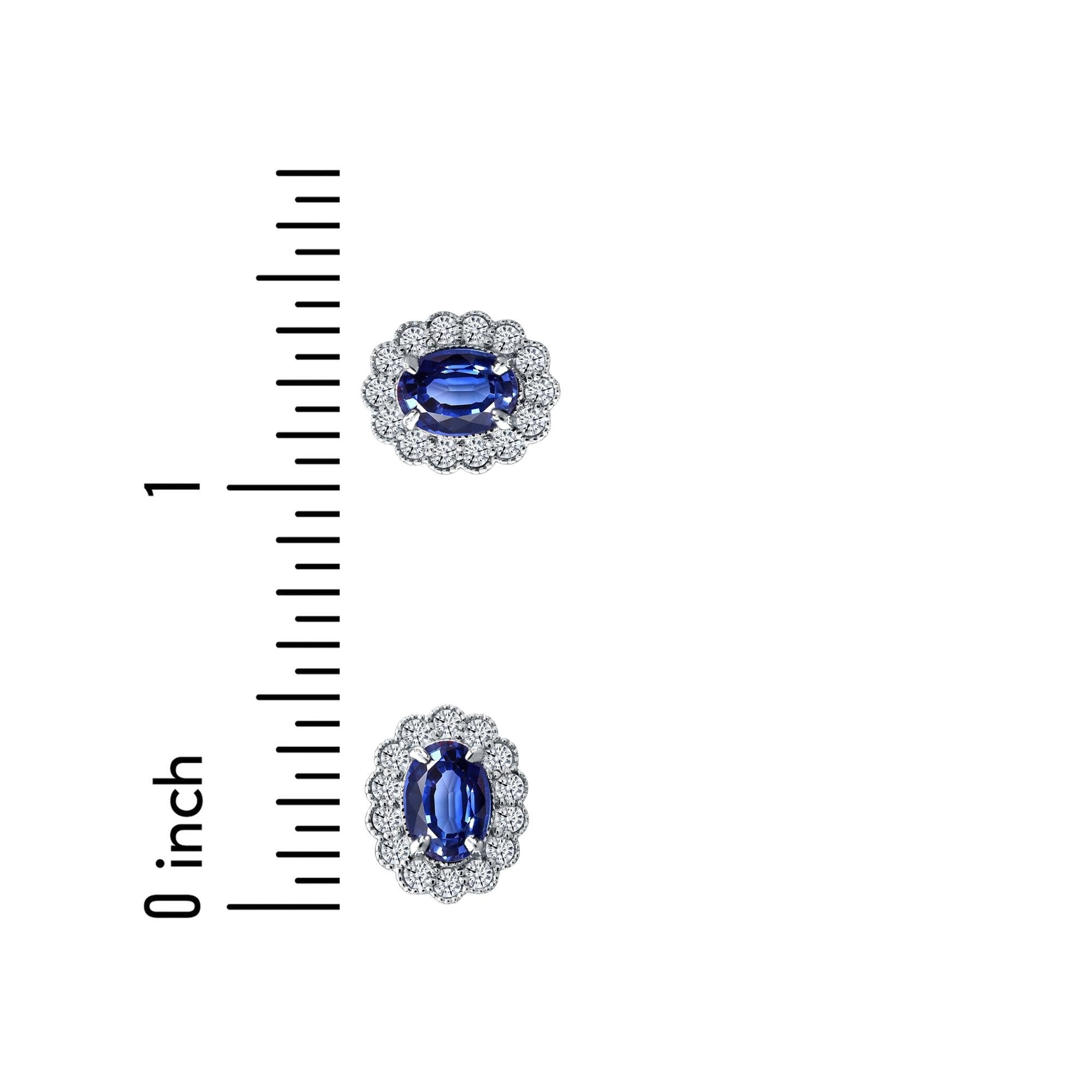 Questi orecchini brillano per la loro sottile eleganza, con uno zaffiro ovale di 7x5 mm circondato da un'aureola di diamanti bianchi rotondi. Questi sono incastonati in una montatura milgrain delicatamente intagliata, incastonata in oro bianco