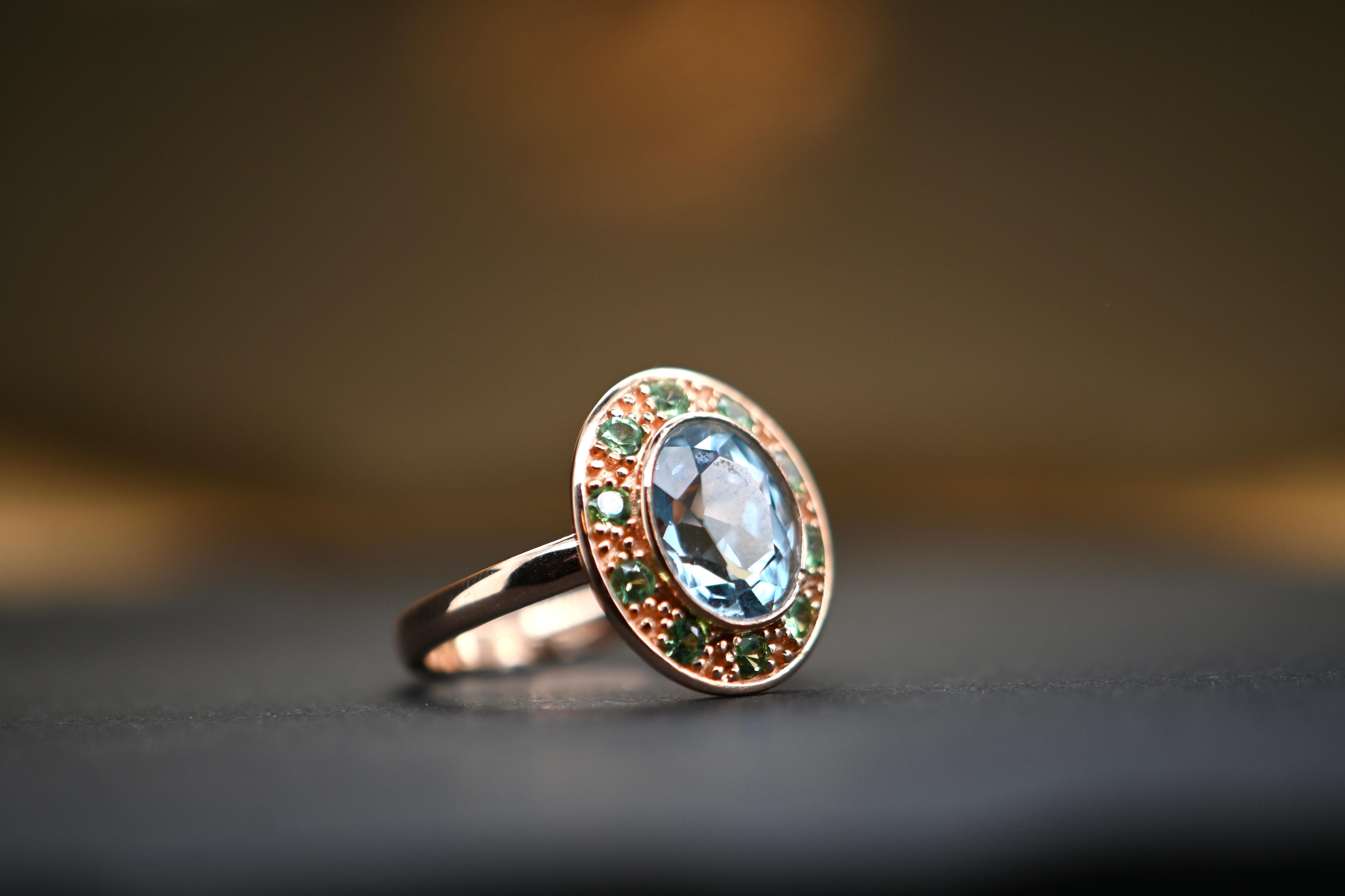 This sumptuous 18-carat gold ring is set with 10 tsavorite stones and a magnificent topaz. Each piece is unique due to the natural topaz stone, whose color nuances and details may vary from one creation to the next. Initially available in size 54,