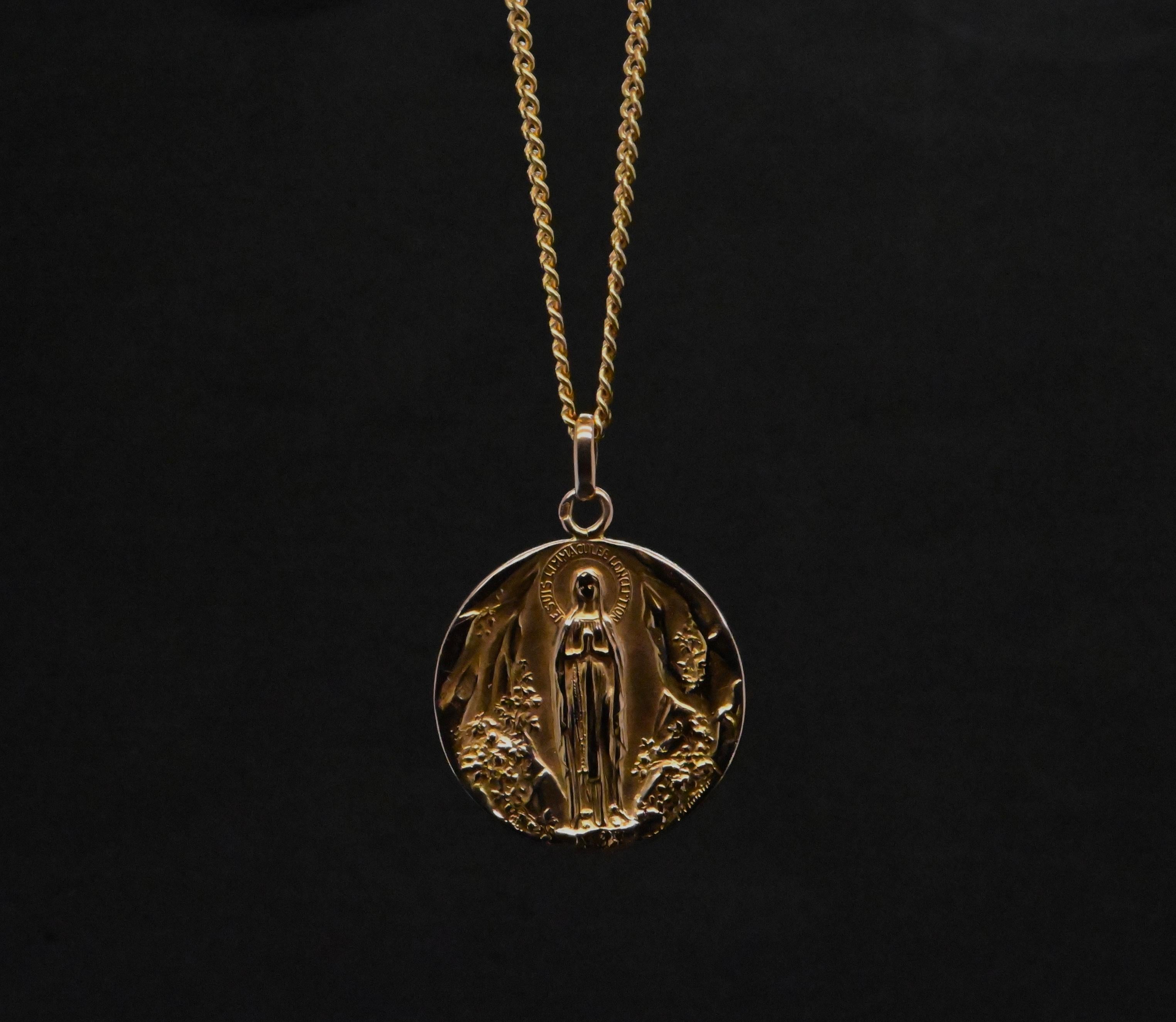 This 18-carat rose gold medallion is a tribute to fine craftsmanship and faith. Certified by a poinçon de maître, it guarantees the quality of 750 thousandths gold. 

In the center of the medallion, the Virgin Mary is depicted with an aura of