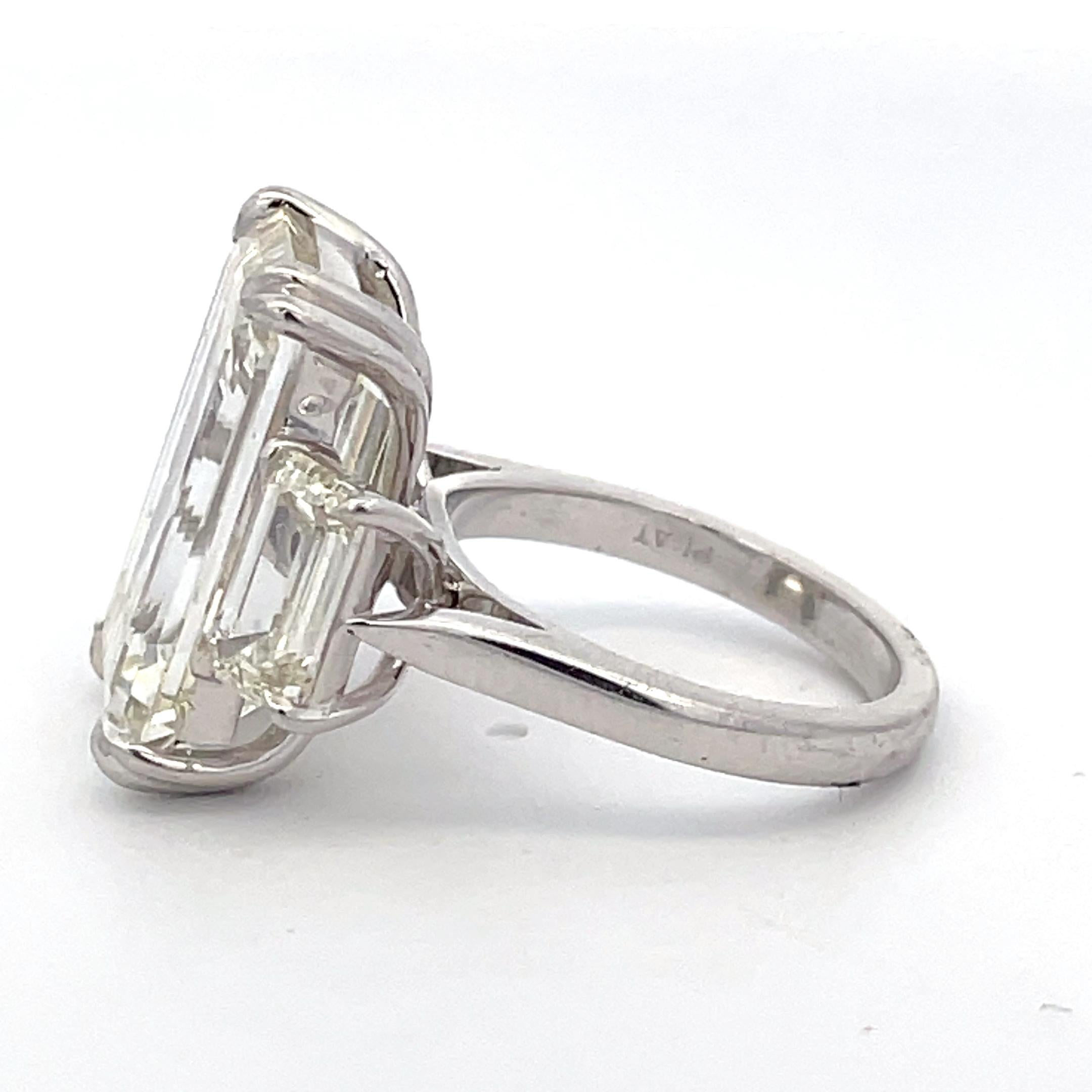 3-stone ring in platinum with Emerald cut K VS2 GIA certified diamond center stone and emerald cut side stones in claw prong set. D18.14 (CTR 15.14 D 3.00)