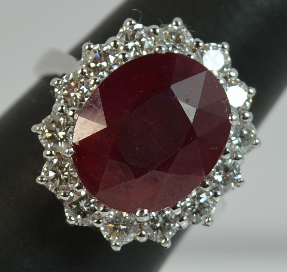 
A beautiful Ruby and Diamond cluster ring.

​Designed with a ruby of oval cut to measure 10.8mm x 13.1mm in a four claw setting. Weighing an impressive 8.40 carats.

Surrounding are fourteen natural round cut diamonds, 1.50 carats. Very clean and