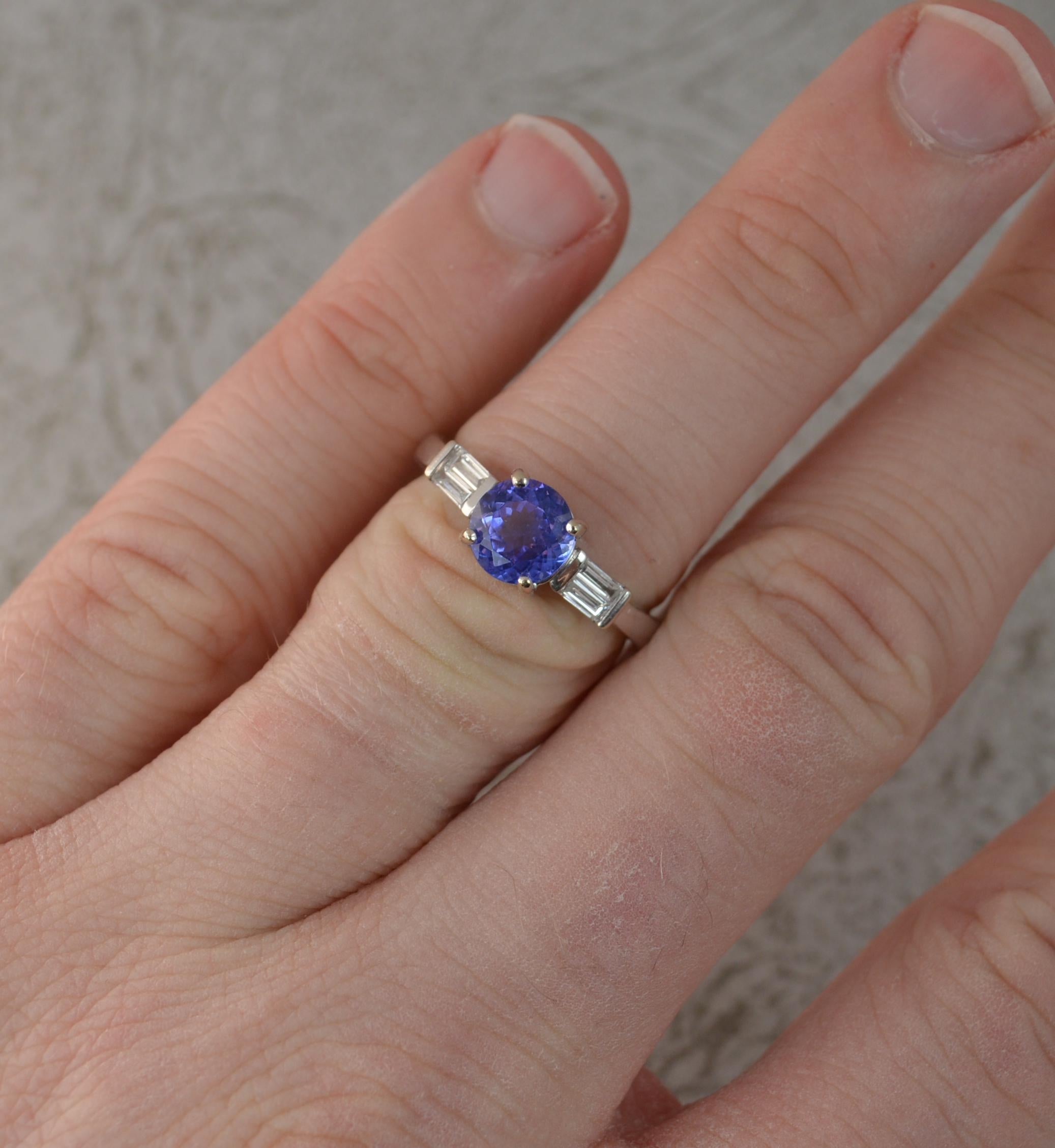 A wonderful engagement type ring.
Solid 18 carat white gold example.
Set with a round cut tanzanite to centre, 6.4mm diameter, with intense colour.
To each side are two vs clarity baguette cut diamonds. 0.30 carats total.
Protruding 5.7mm off the
