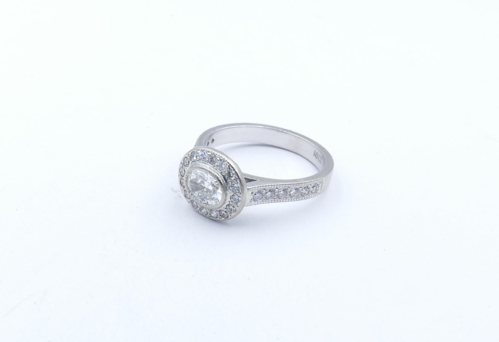 This Ring features a central Oval Cut Diamond of 3 quarters of a Carat, G/H Colour, Si1 Clarity.
28 Round Brilliant Cut Diamonds weight 0.4 Carat and the same high quality, are set around the Centre Stone & in the shoulders of the Ring. 
Finger Size