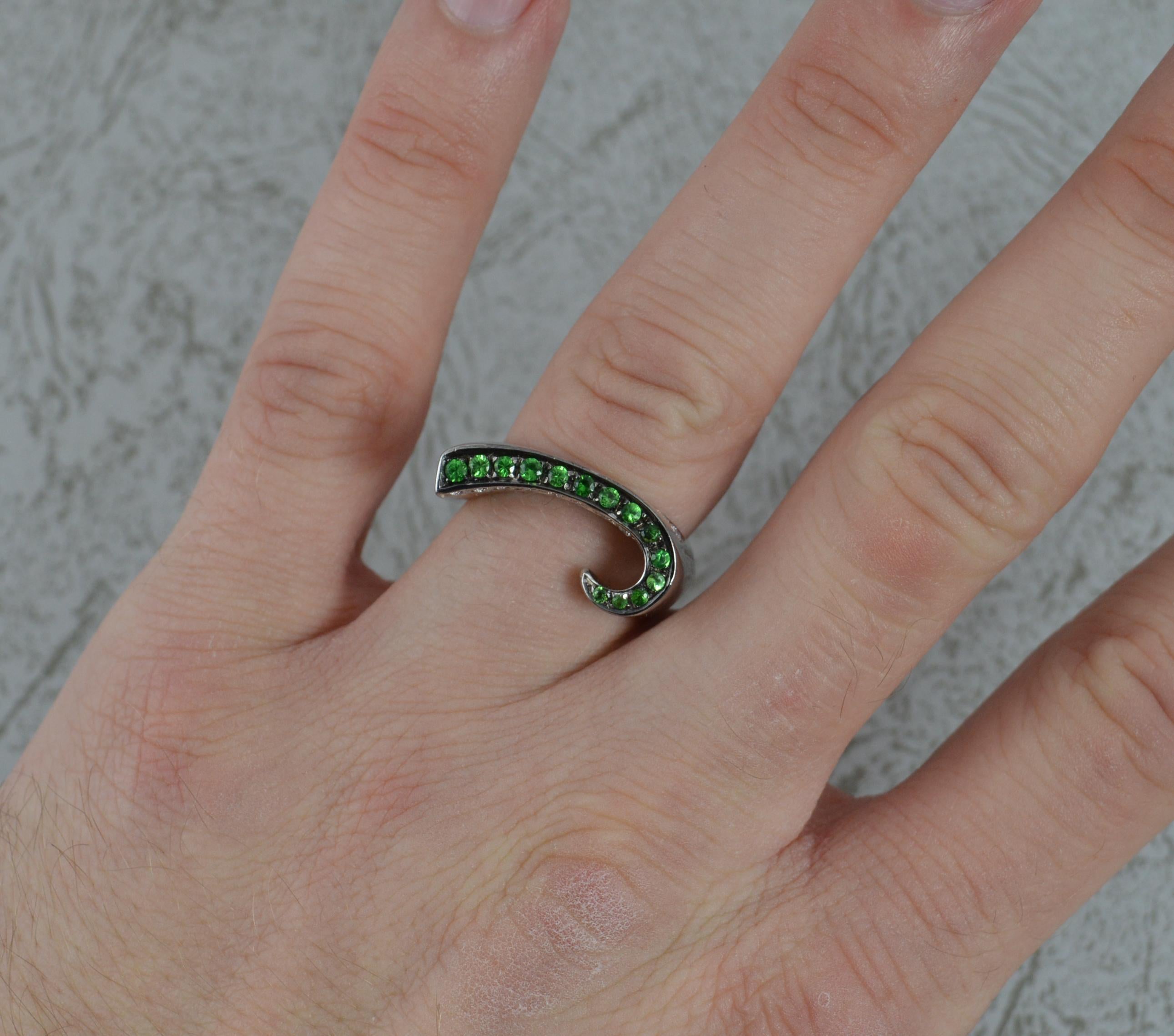 A stunning 18 white carat gold, green garnet and diamond ring.
18 carat white gold shank and setting with blackened setting for the garnets.
Designed as a four sided band with wave like finish.
Set with many demantoid green garnets and vs grade