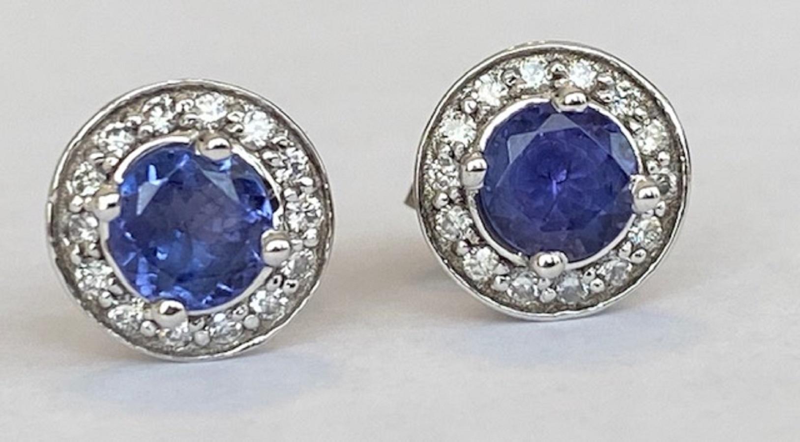 These elegant 18-carat white gold halo earrings feature stunning totalling 1.00 ct tanzanite gemstones, known for their deep violet-blue hue. Each tanzanite is beautifully encircled by a halo of brilliant diamonds, enhancing their brilliance and