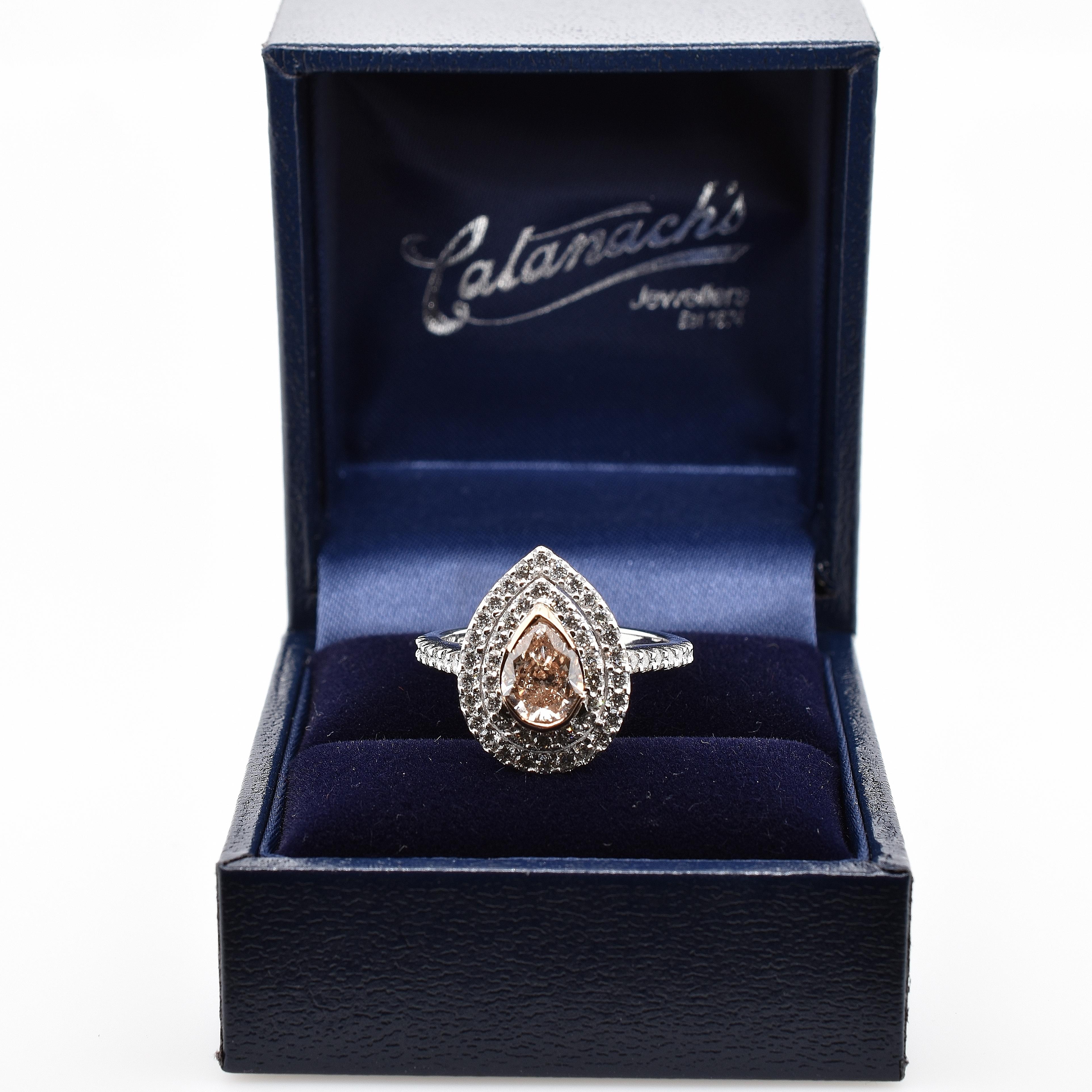 18ct white gold pear shaped peach diamond and two row brilliant diamond halo cluster ring. The natural peach diamond is 0.83ct centre bezel set in 18ct rose gold and white diamonds are claw set as halo and shoulders. 58 round brilliant cut diamonds