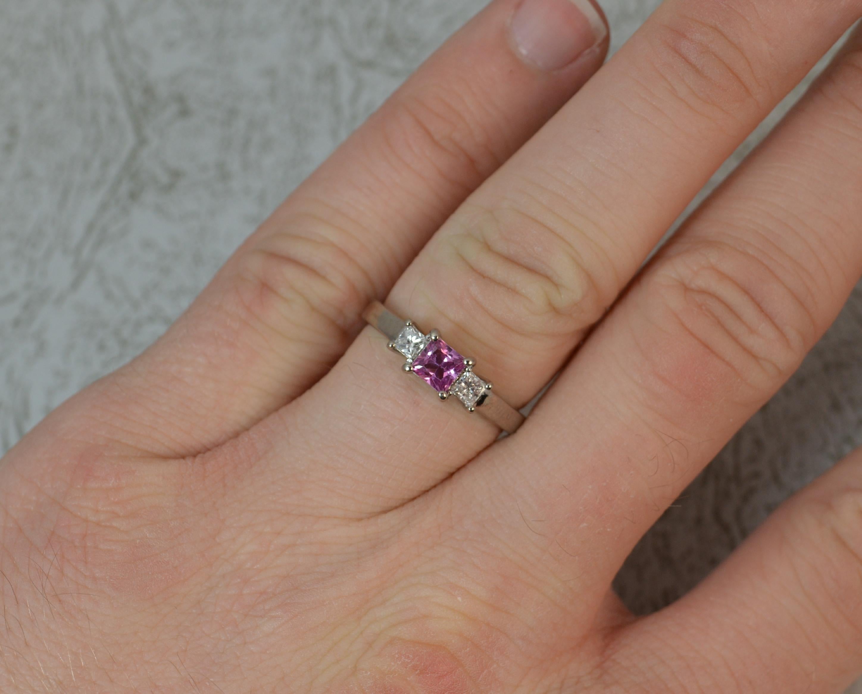 A beautiful contemporary pink Sapphire and Diamond trilogy ring of art deco design.
Solid 18 carat white gold example.
Designed with a 4.1mm x 4.1mm princess cut pink sapphire to the centre with Vs princess cut diamond to each side. 
0.2 carat
