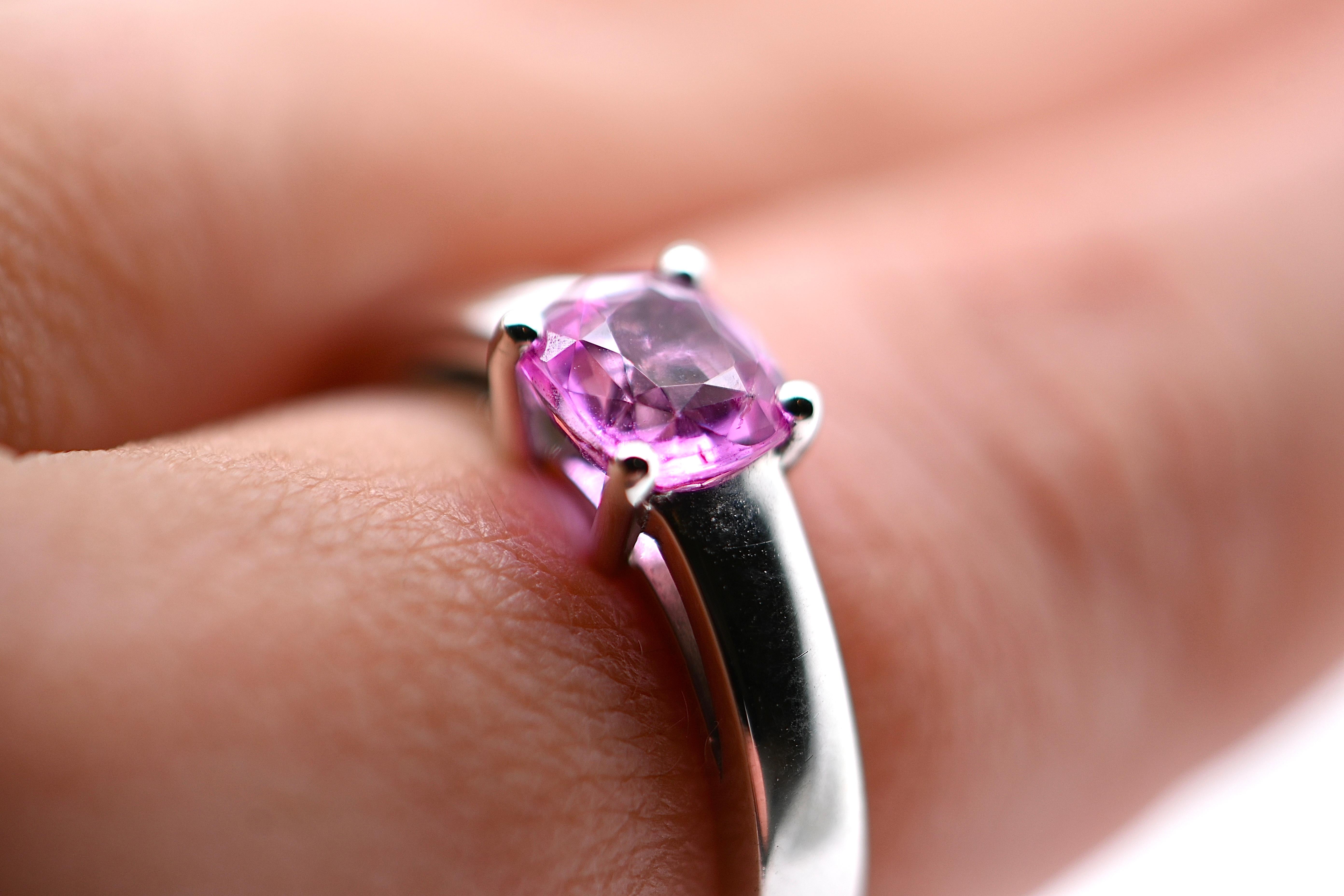 Dieser exquisite Ring ist aus 18 Karat Weißgold gefertigt und zeigt in seiner Mitte einen atemberaubenden rosa Saphir im Kissenschliff mit einem Gewicht von 1,36 Karat. Der leuchtende rosa Farbton des Saphirs verleiht ihm einen Hauch von