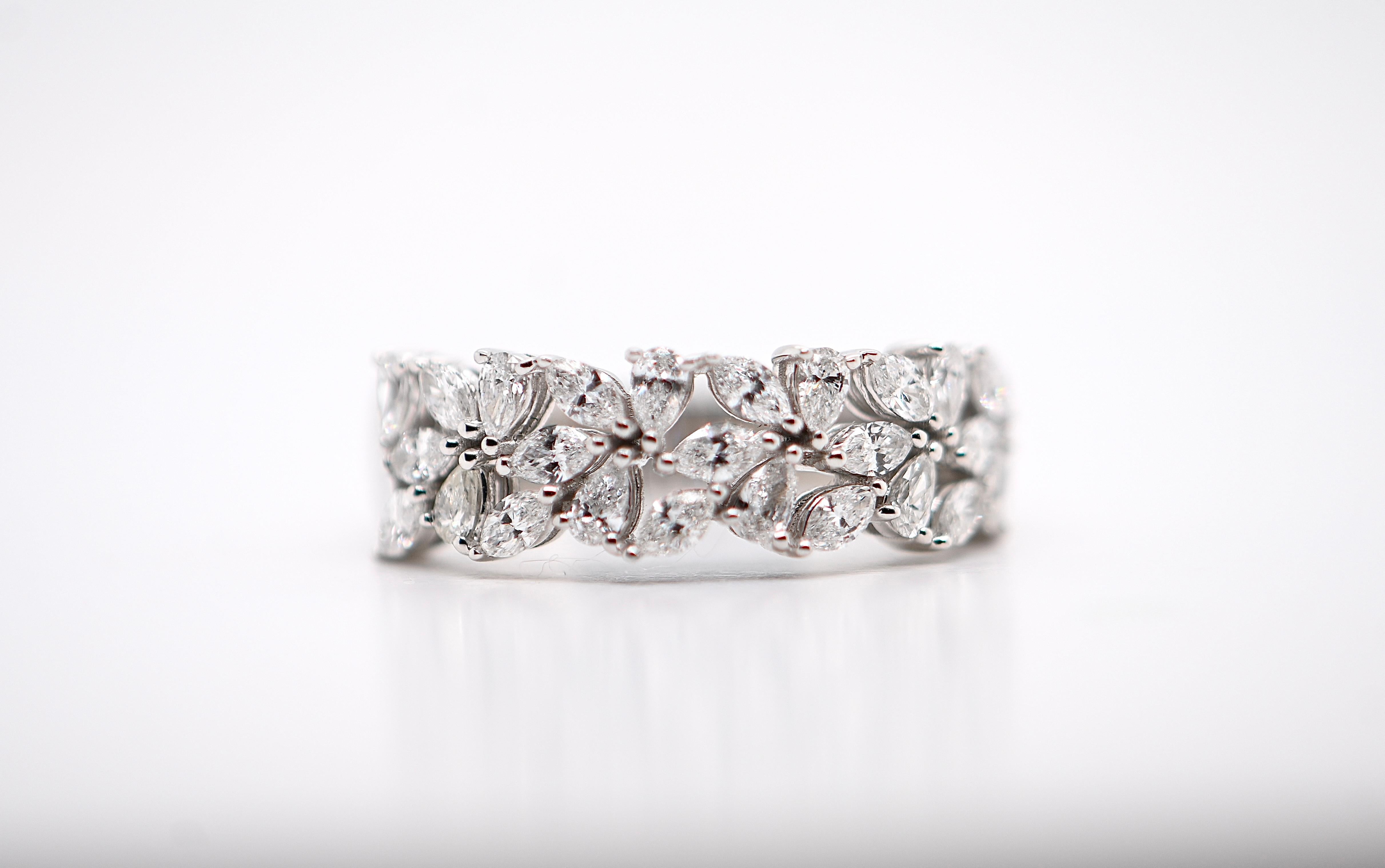 This exquisite 18-carat white gold ring features a stunning band design adorned with 1.010 carats of G-color diamonds. The diamonds are artfully arranged to form delicate, petal-shaped flowers, creating a magnificent floral motif. Each diamond is