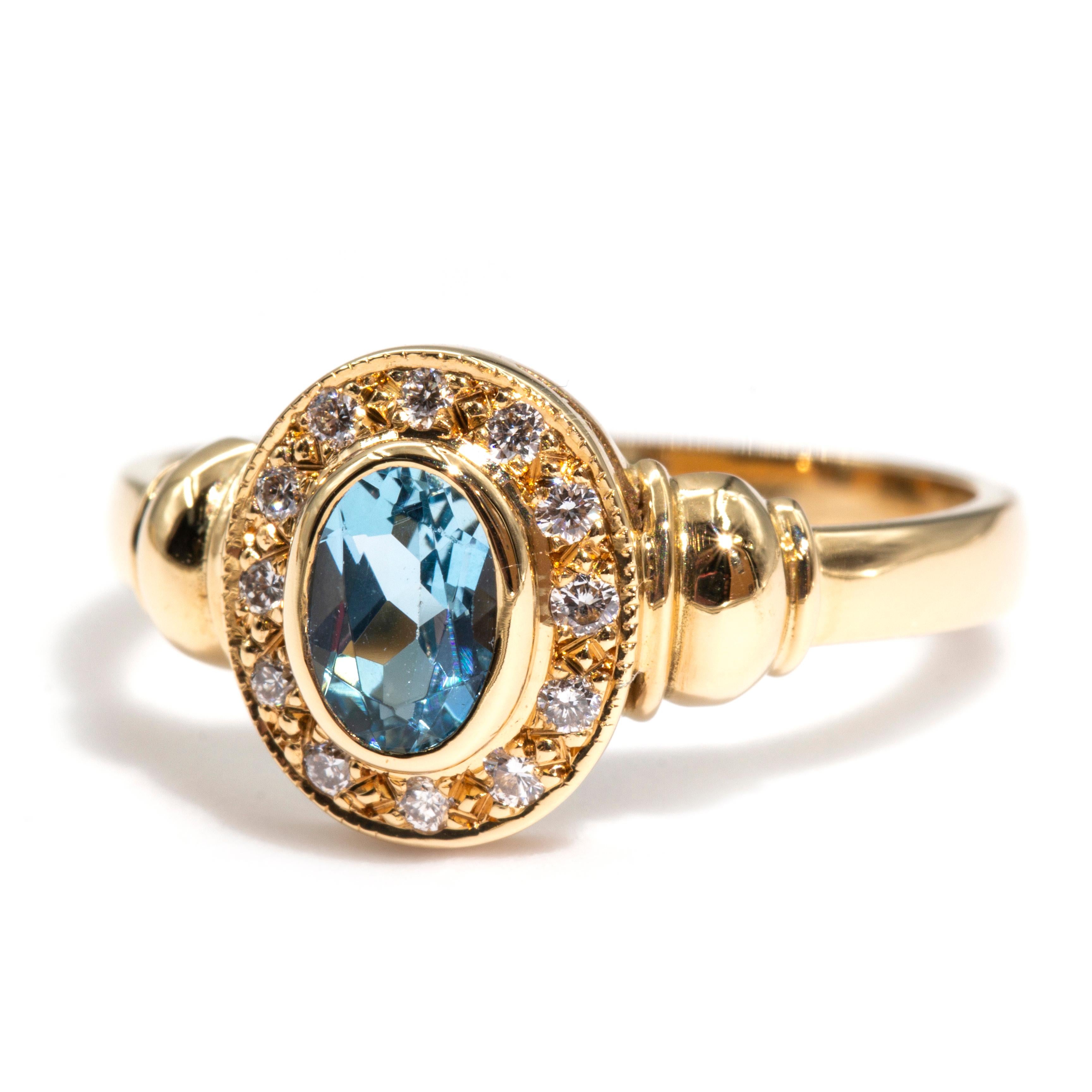 Crafted in 18 carat yellow gold is this charming vintage cluster ring that features a lovely blue oval aquamarine and is surrounded by a halo of sparking round brilliant cut diamonds. We have named this vintage splendour The Scarlett Ring. The