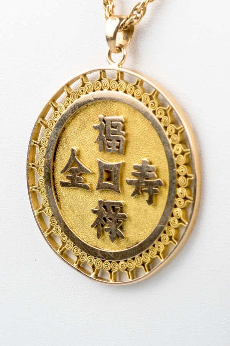 18-carat yellow gold necklace designed with a rope mesh and a spring ring clasp.18-carat yellow gold medallion pendant with different Chinese symbols on each side and traditional patterns. 
Unique, this necklace is ideal to bring a touch of elegance