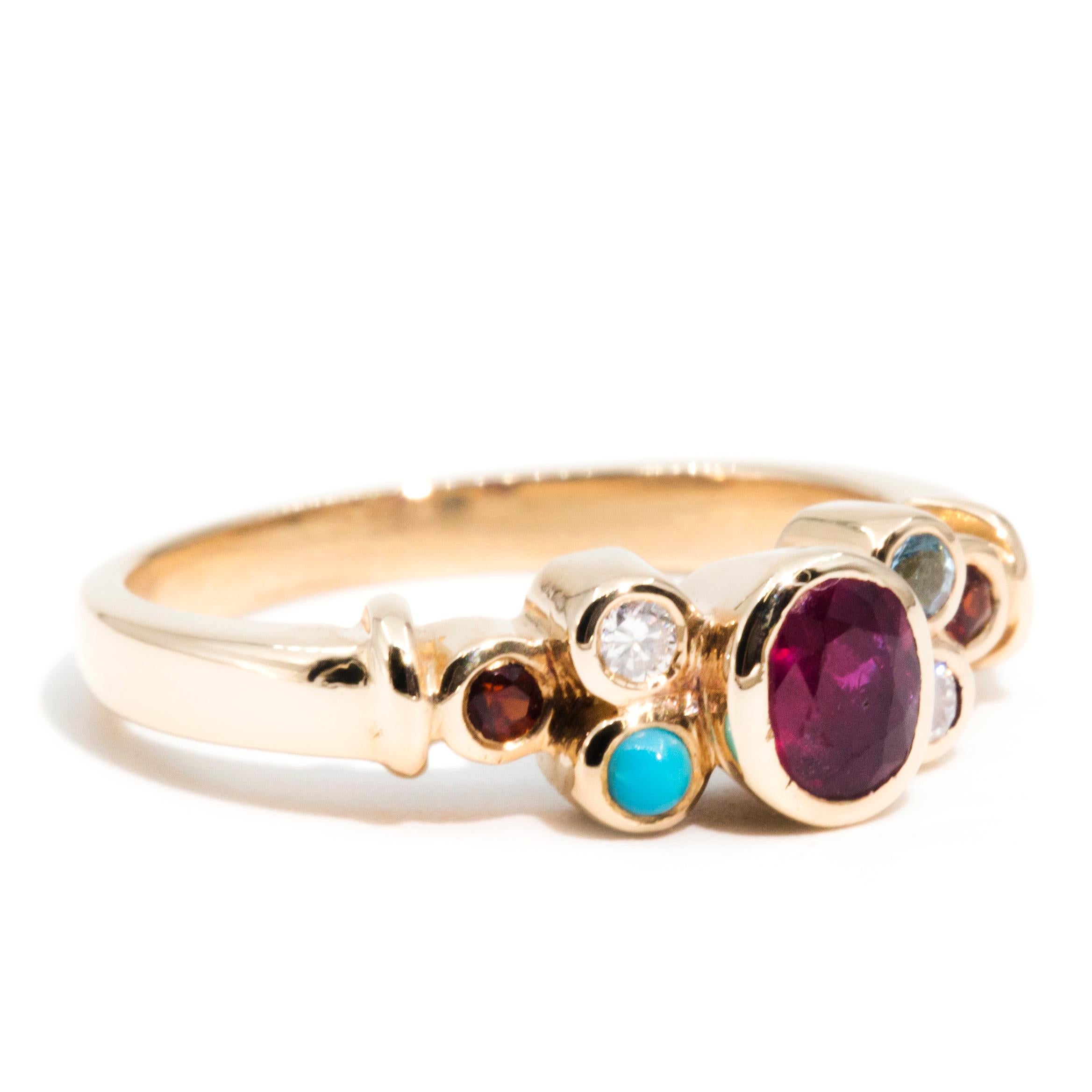 Forged in 18 carat gold, this vibrant vintage ring features a polished band rising into three tiers of gemstone clusters with opulent turquoises, garnets, aquamarines, and sapphires. At the centre is an alluring 0.41 carat oval faceted deep red