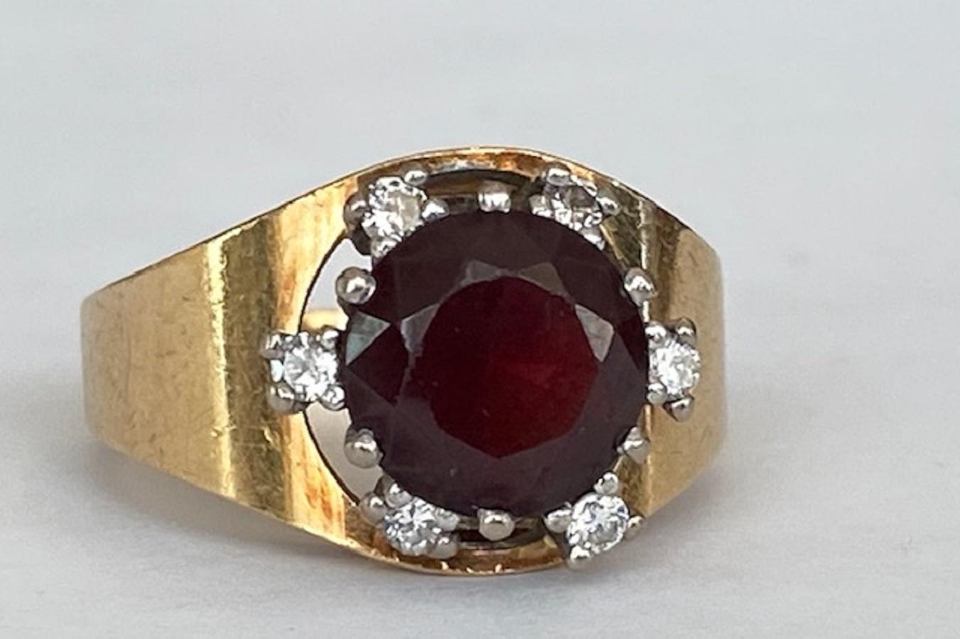 En bon état, bague vintage entourage en or jaune 18kt sertie d'un grenat rond d'environ 3.00 crt et entourée de 6 diamants de taille brillant d'un total d'environ 0.25 crt, qualité H/SI.
Teneur en or : 18 KT (poinçonné)
Grenat ) - environ 3,00
