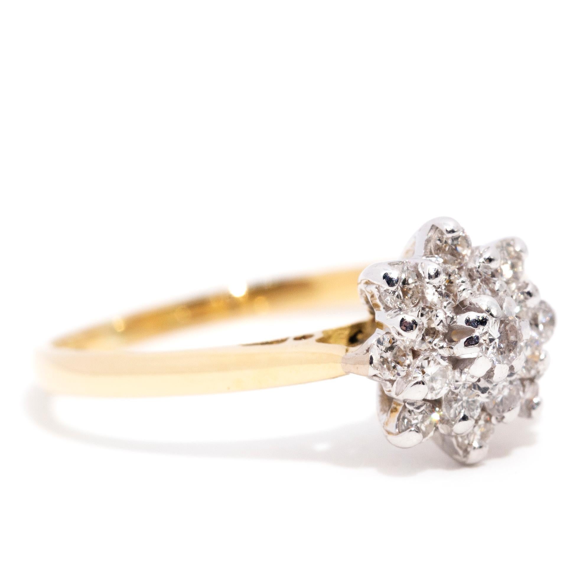 Elegantly crafted in 18 carat yellow gold, this lovely vintage cluster ring is a delight. A high polish band moves into tapered shoulders holding a shimmering starburst cluster. At the centre of the cluster is a sparkling round brilliant diamond