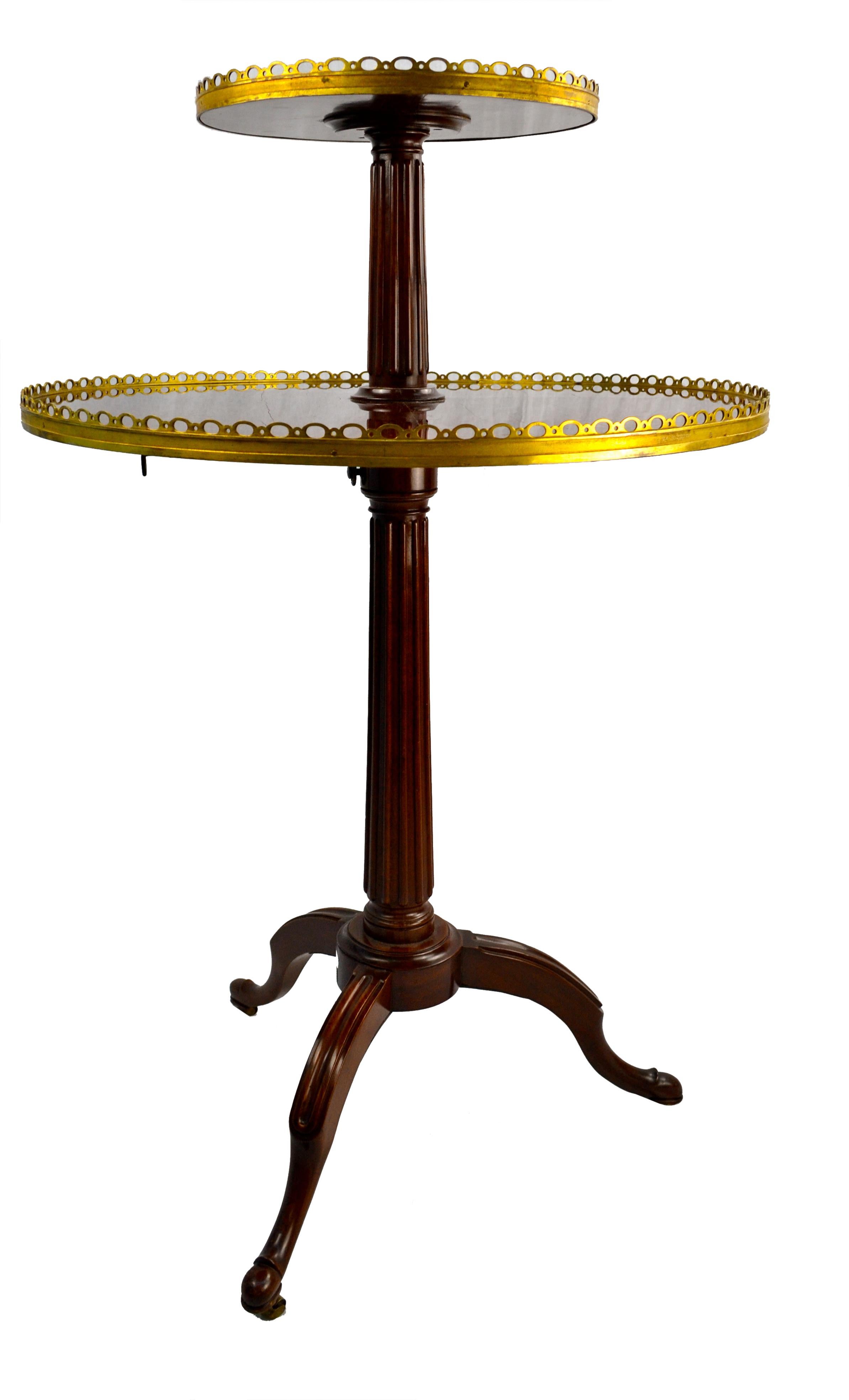 A late 18th century Louis XVI desert table or as is often referred to a ‘dumb-waiter’ in mahogany with gilt metal galleries; the top tier is adjustable in height; the fluted central column resting on three splayed legs with original castors.