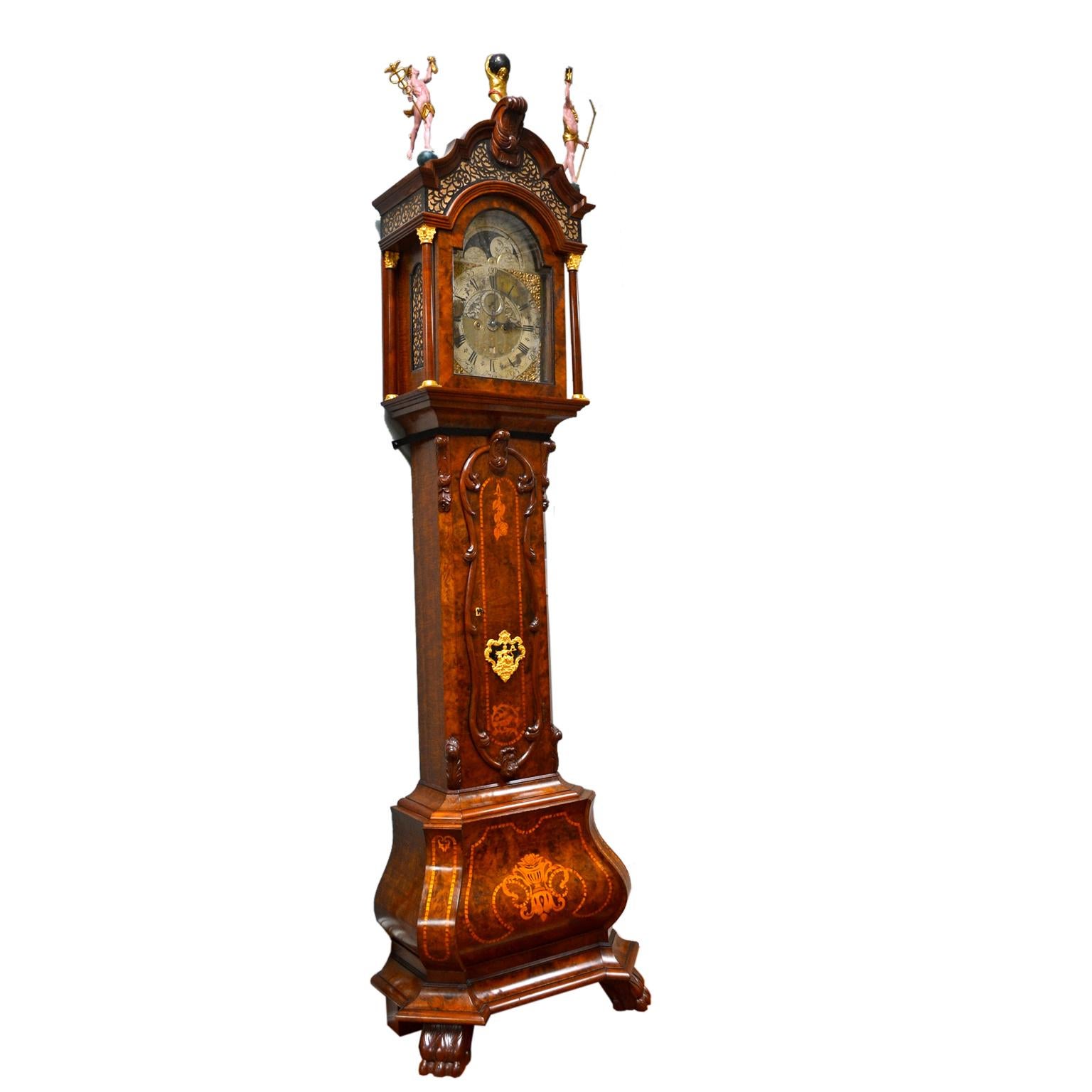 A walnut, burr-walnut and inlaid Dutch longcase clock by W.V Dadelbeek, Utrecht. The case of typical form, trunk door with feather banding, bombe base, original carved painted and parcel gilt wood figural finials of Atlas, Father Time and Mercury.