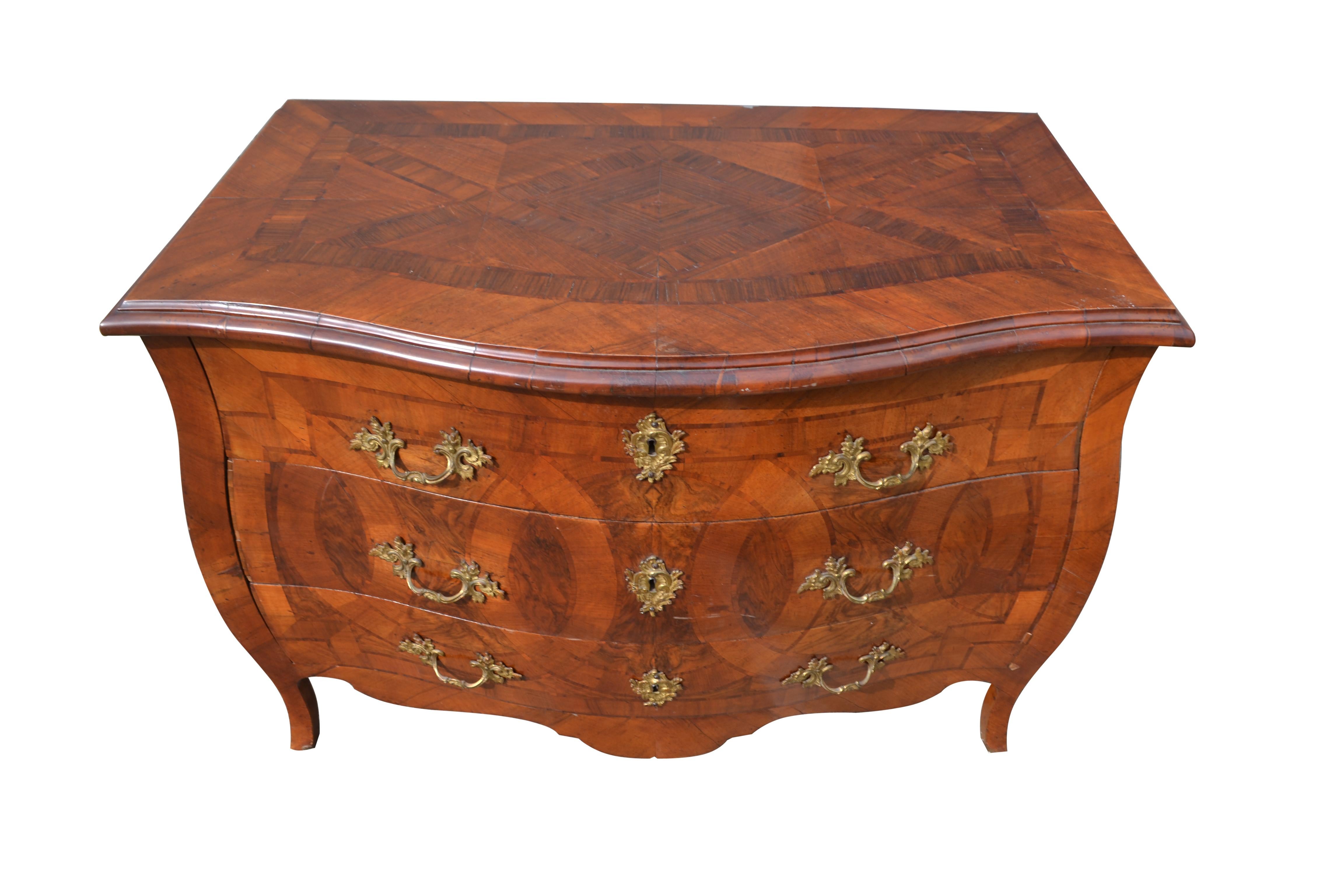 A fine Italian mid-18th century figured-walnut bombe three drawer commode; the commode is inlaid on all visible sides including the top in attractive olive wood and walnut, and it sits on tall elegant swept feet. The commode has its original locks,