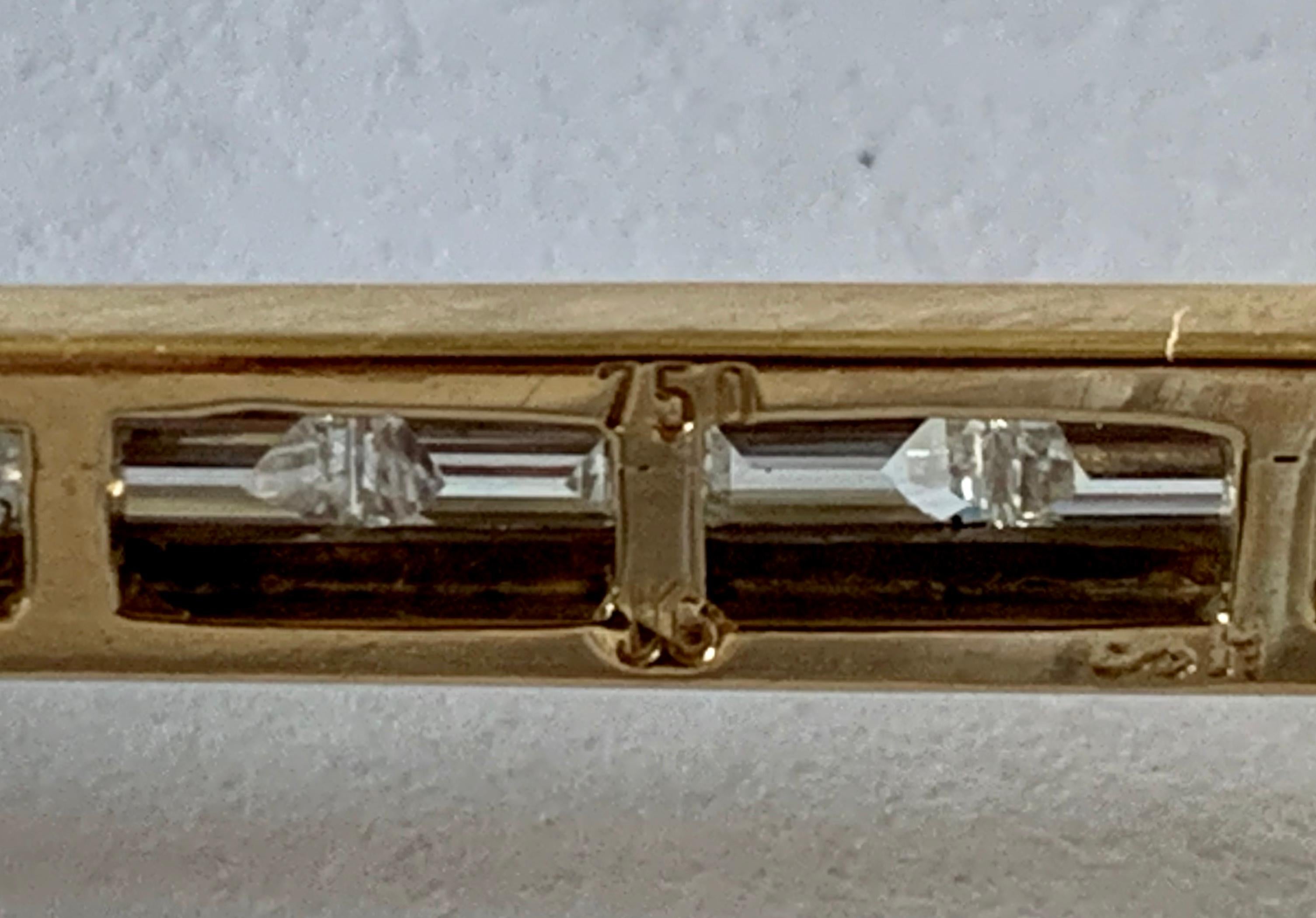 Elegante Brosche aus 18 K Gelb- und Weißgold, besetzt mit einem herzförmigen Saphir-Cabochon und einem birnenförmigen Rubin. Beide Edelsteine sind durch einen Stab verbunden, der vollständig mit 14 Baguette-Diamanten von 2,20 ct, F, besetzt ist. 