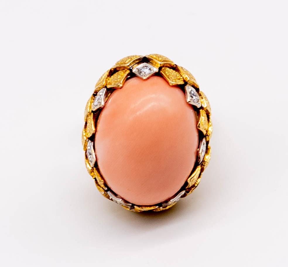 A perfect harbinger of summer, this beautiful and feminine ring consists of a large cabochon of medium peach colored coral ( 20.5mm x 16.2mm)  set atop a base of rich gold quadrangles and ovals of textured gold.  The petite diamonds ( 8 in all,