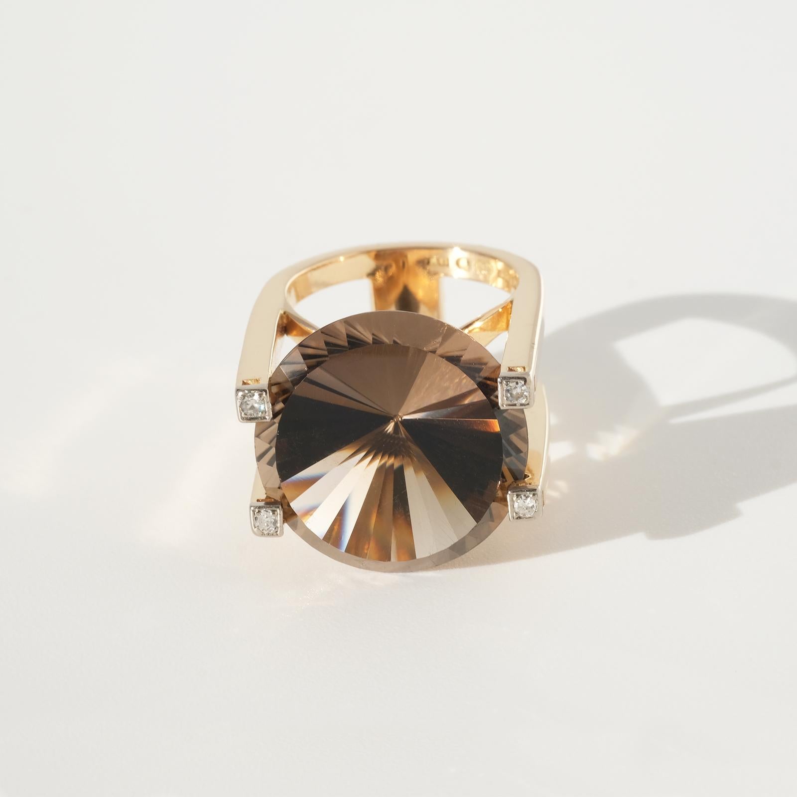 This luxurious 18 karat gold, smokey quarts and diamond ring has an exquisite design with its high shaped setting and its big brilliant cut smoky quartz. The final touch is the four octagon cut diamonds.

This ring is perfect for the cocktail