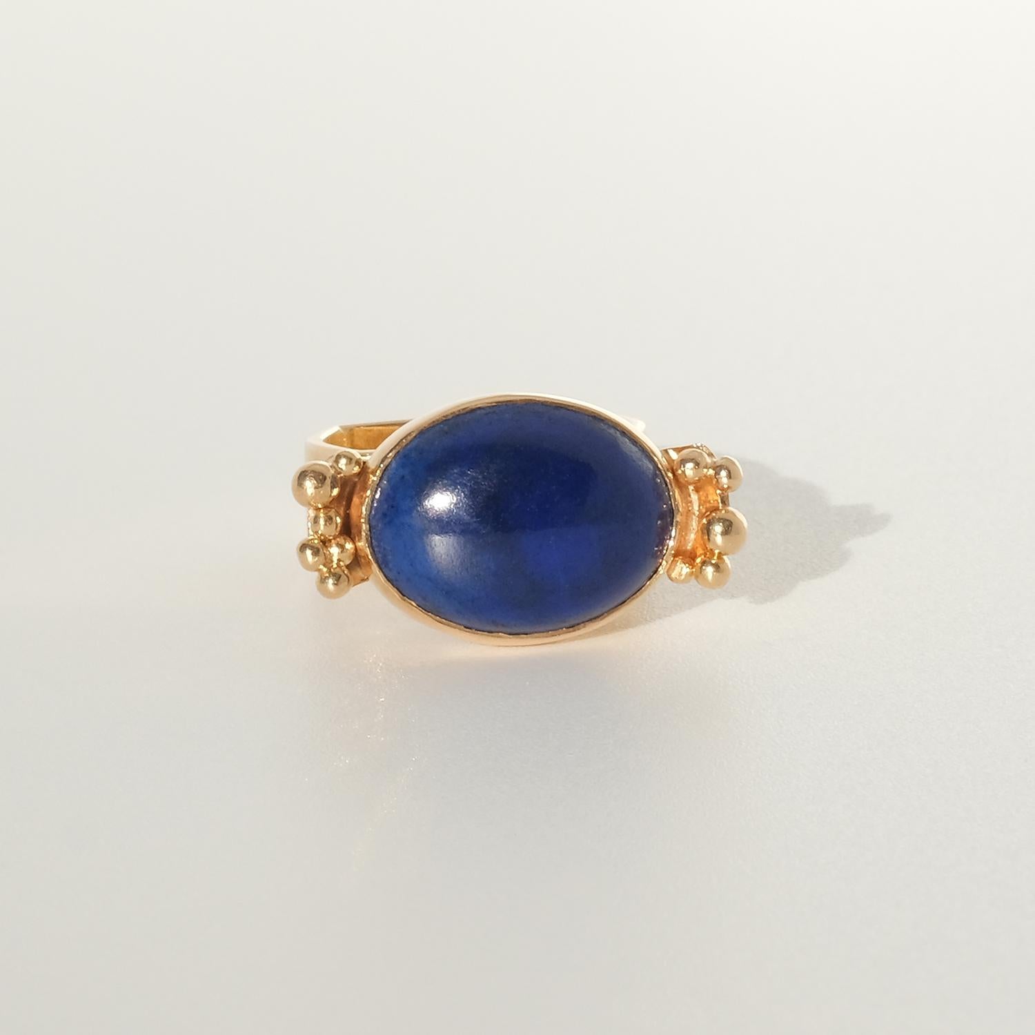 This 18 karat gold ring is adorned with a cabochon-cut grain blue lapis-lazuli stone. The shank of the ring is square shaped and on top of the shoulders of the ring golden bunches of grapes have been placed.

This ring is an eye-catcher which will