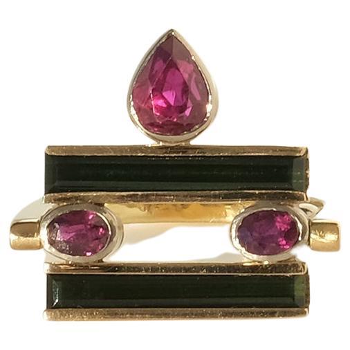 A unusually designed 18k gold ring made by the Swedish goldsmith Mats Eskils (1953-  ). The rings upper part is turnable so that it either can stand up or lay down. The ring is set with tourmaline and rubys.