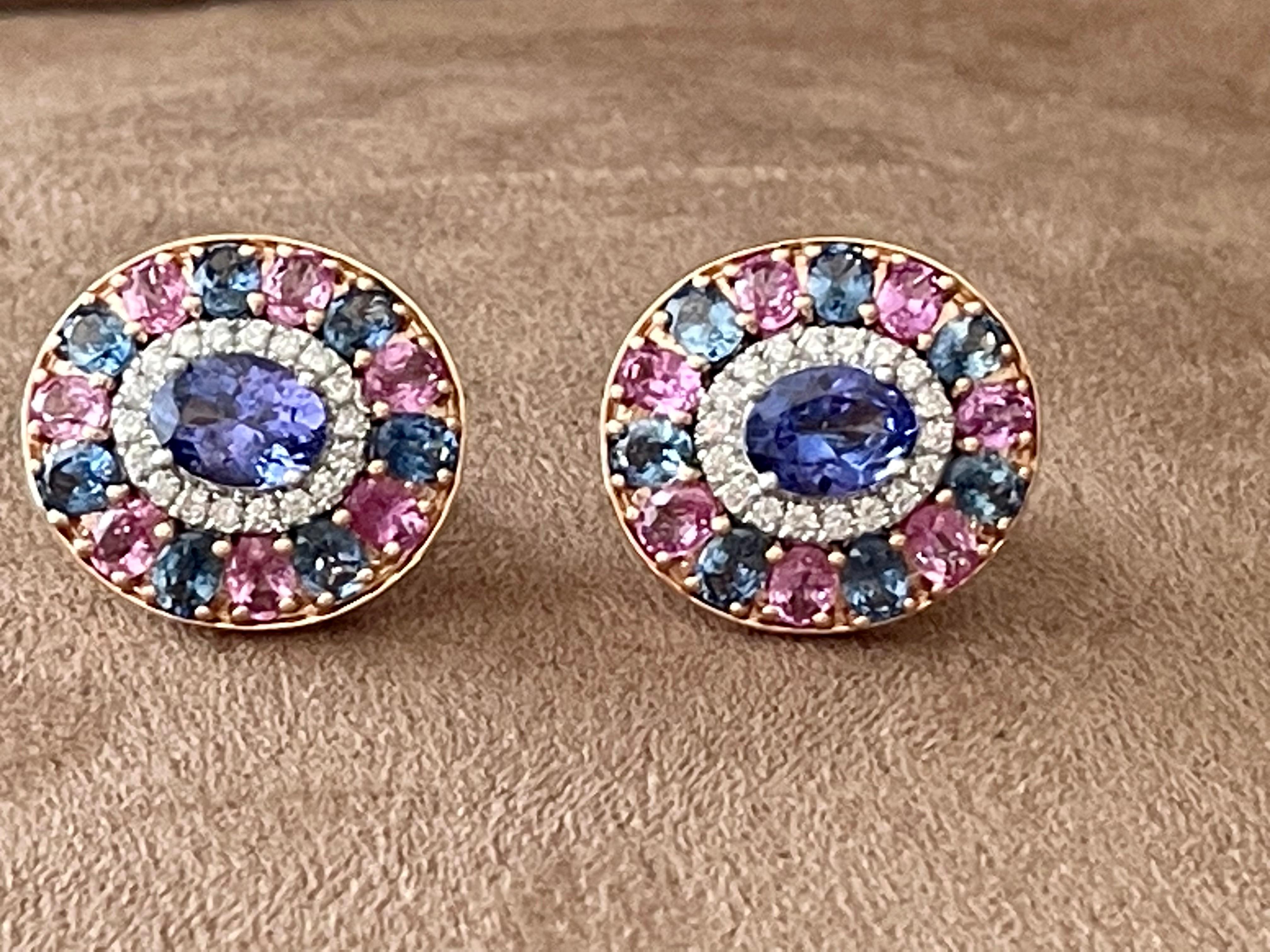 Eine wahrhaft atemberaubende Farbenpracht! Diese hübschen Ohrringe bestehen aus einem mehrfarbigen Cluster mit 2 ovalen Tansaniten von 2,51 ct, 14 blauen Saphiren von 3,521 ct, 36 Diamanten im Brillantschliff von 0,45 ct und 14 rosafarbenen Saphiren