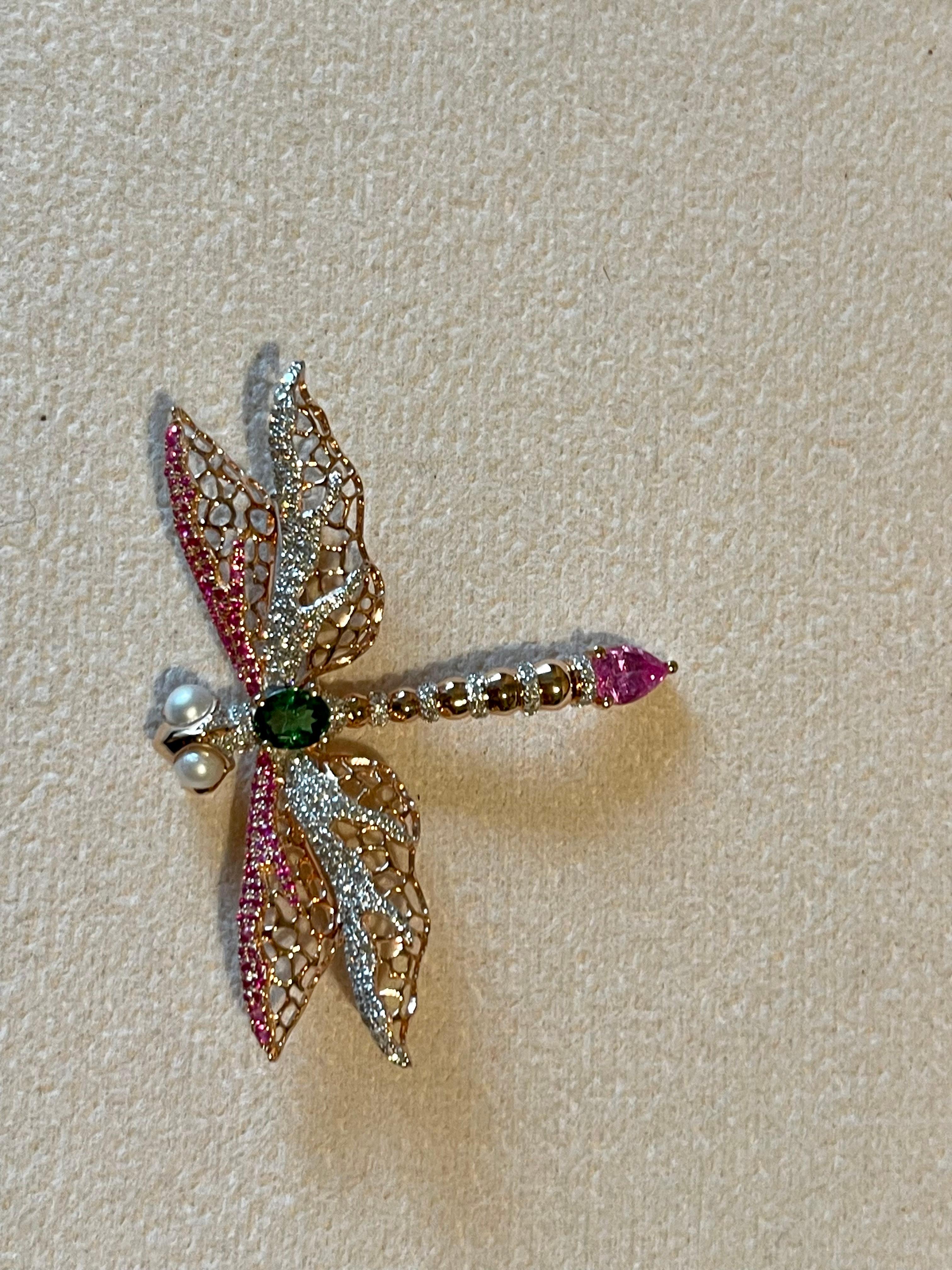This delicate and lovely openwork Dragonfly brooch/pin is clearly inspired by the era of Art Nouveau. 
Made in warm 18 K rose Gold it is featuring an oval vivid green Tsavorite weighing 0.37 ct, 1 pear shape pink Sapphire weighing 0.52 ct, 76 round