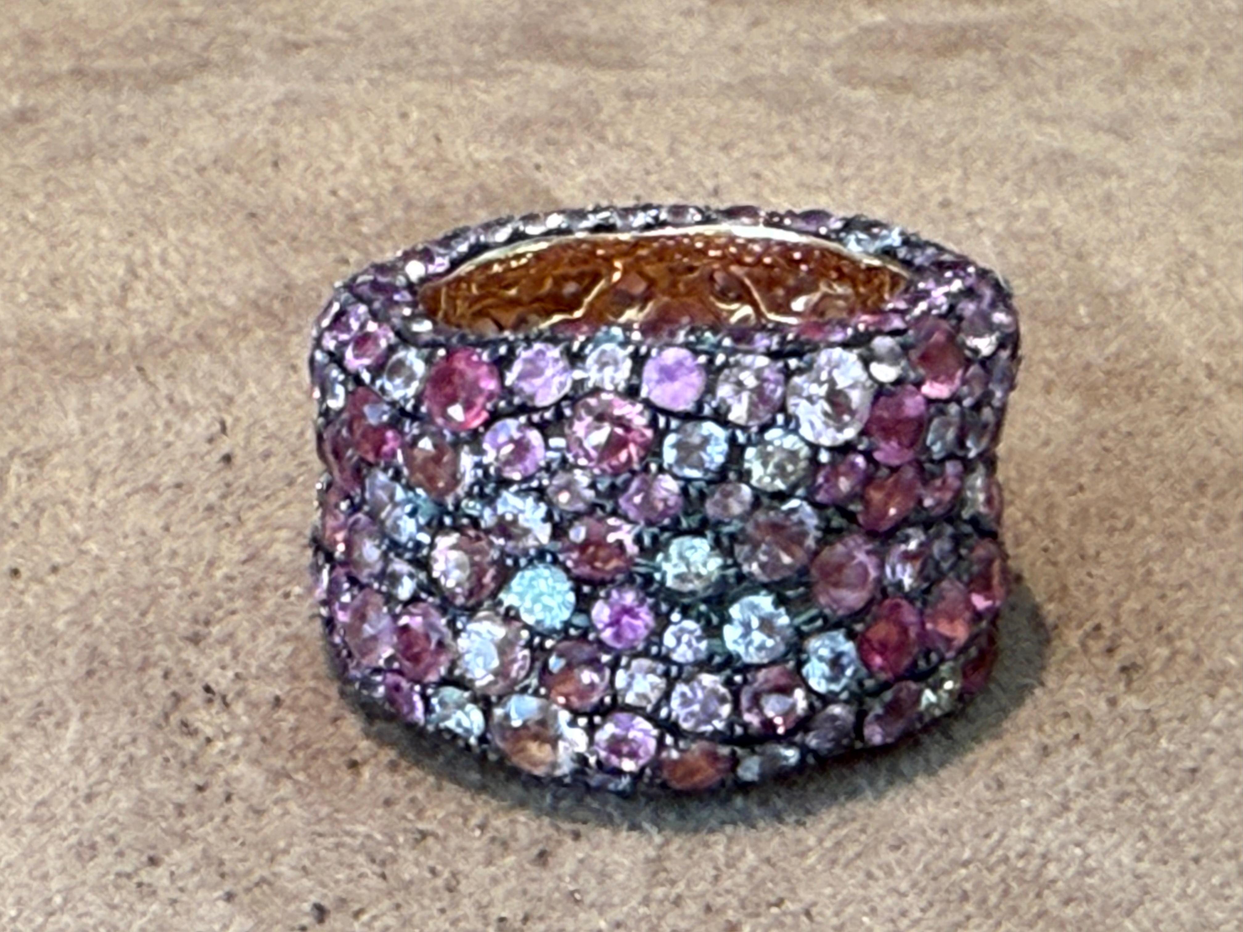 Un sofisticato anello a fascia realizzato in oro rosa 18 K. con 191 zaffiri rotondi di varie tonalità pastello di rosa.  circa 8 carati, e 10 diamanti rotondi taglio brillante del peso di 0,50 carati,  in una raffinata cornice di pavé. Per creare un