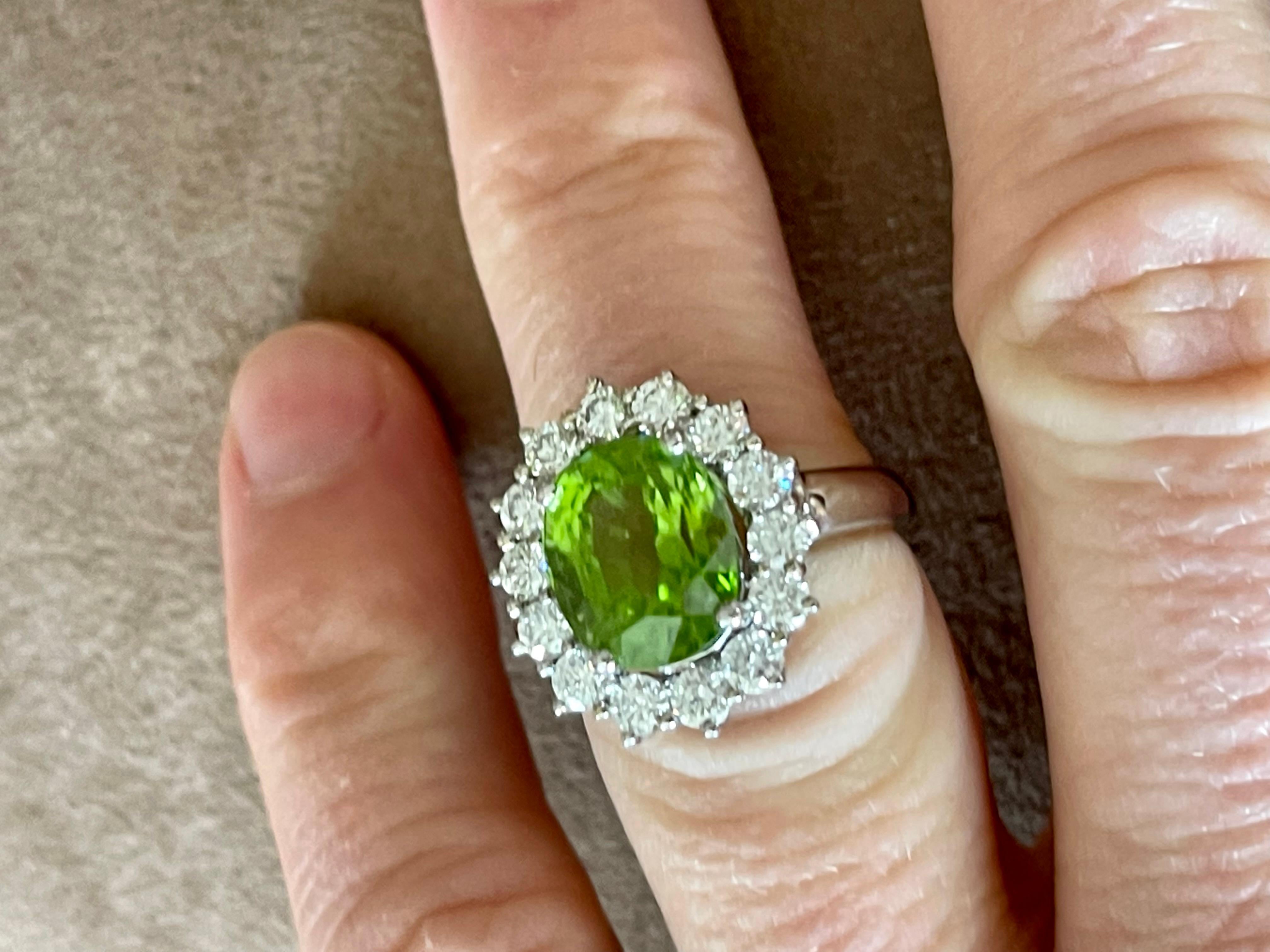 An 18 K whitel Gold Ring that contains an oval Peridot weighing 10.26 ct and 18 brilliant cut Diamonds weiging 1.61 ct. 
The face of the ring measures 1.9 cm tall by 1.55 cm wide. It is stamped with the makers mark and 750. 
The ring size is