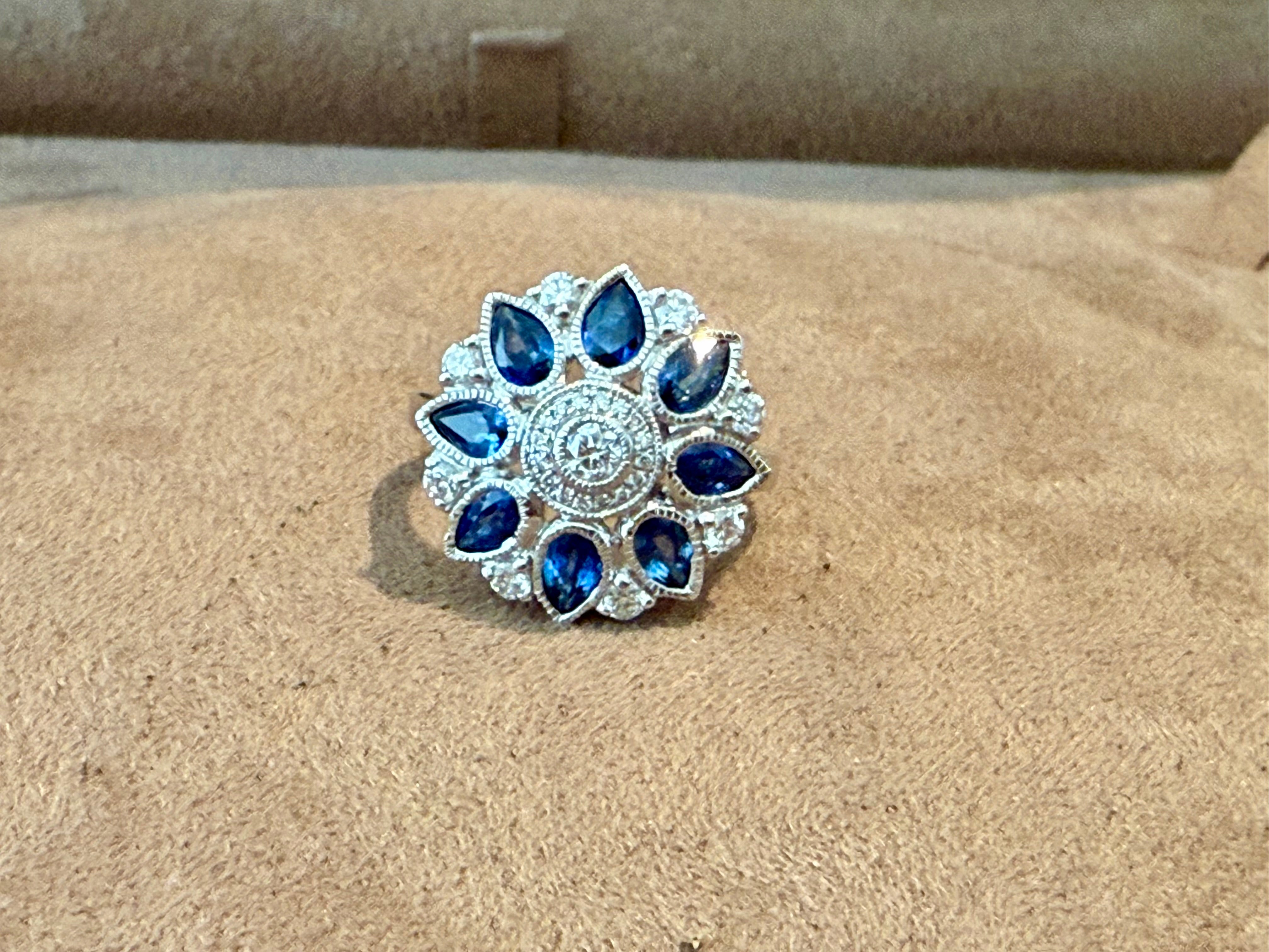 This beautiful 18 K white Gold Ring is inspired by the Art Déco period/style, the halo ring features round H color SI clarity brilliant cut Diamonds with a total weight of 1 ct and is surrounded by 8 oval cut blue natural sapphires with a total