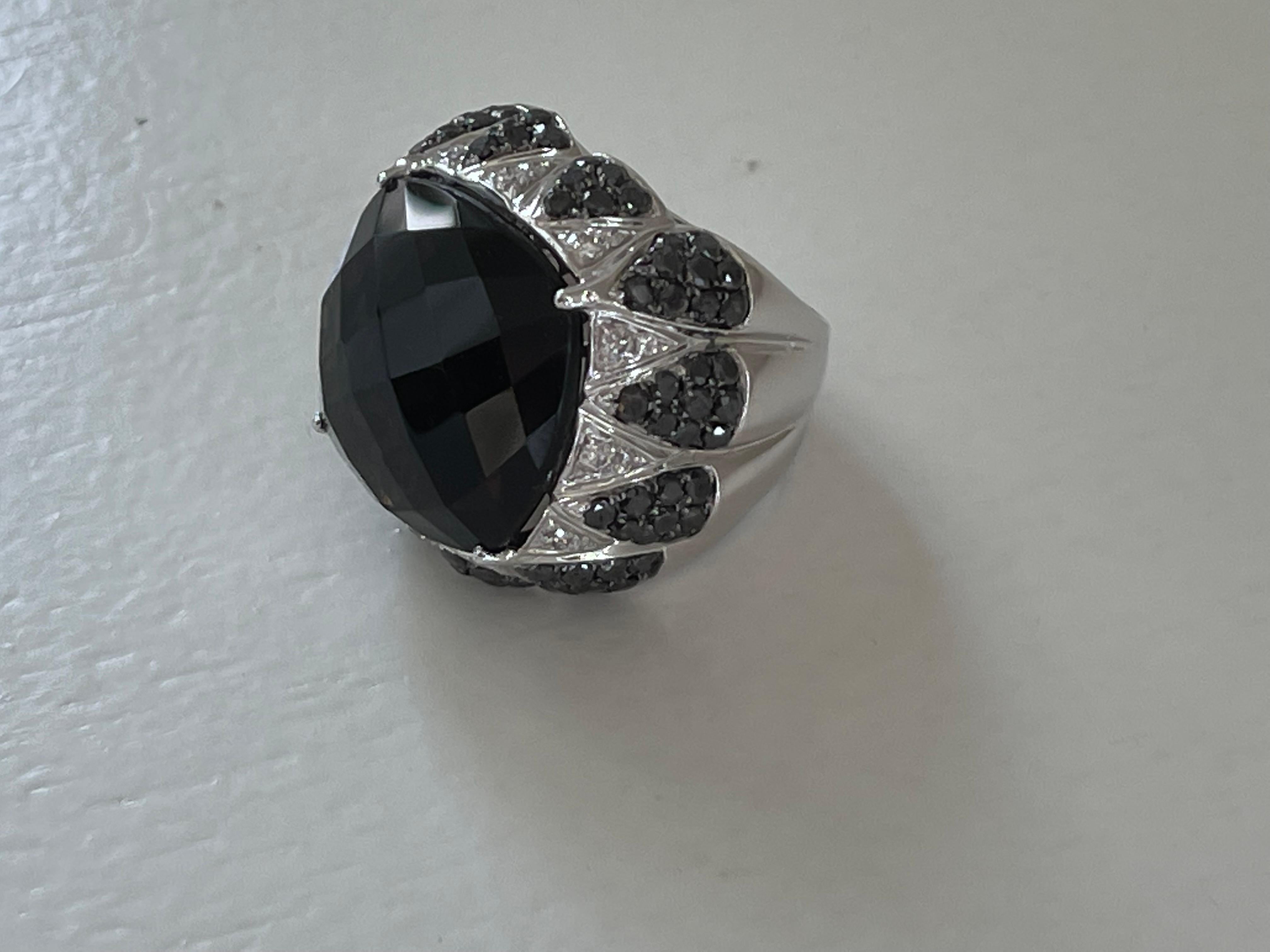 This stunning cocktail ring features a claw set single fancy cut Smoky Quartz center gemstone in a breathtaking 18k white gold setting accented with 96 black Diamonds weighing approximately 
2.30 ct and and 24 white Diamonds weighing 0.46 ct. A real