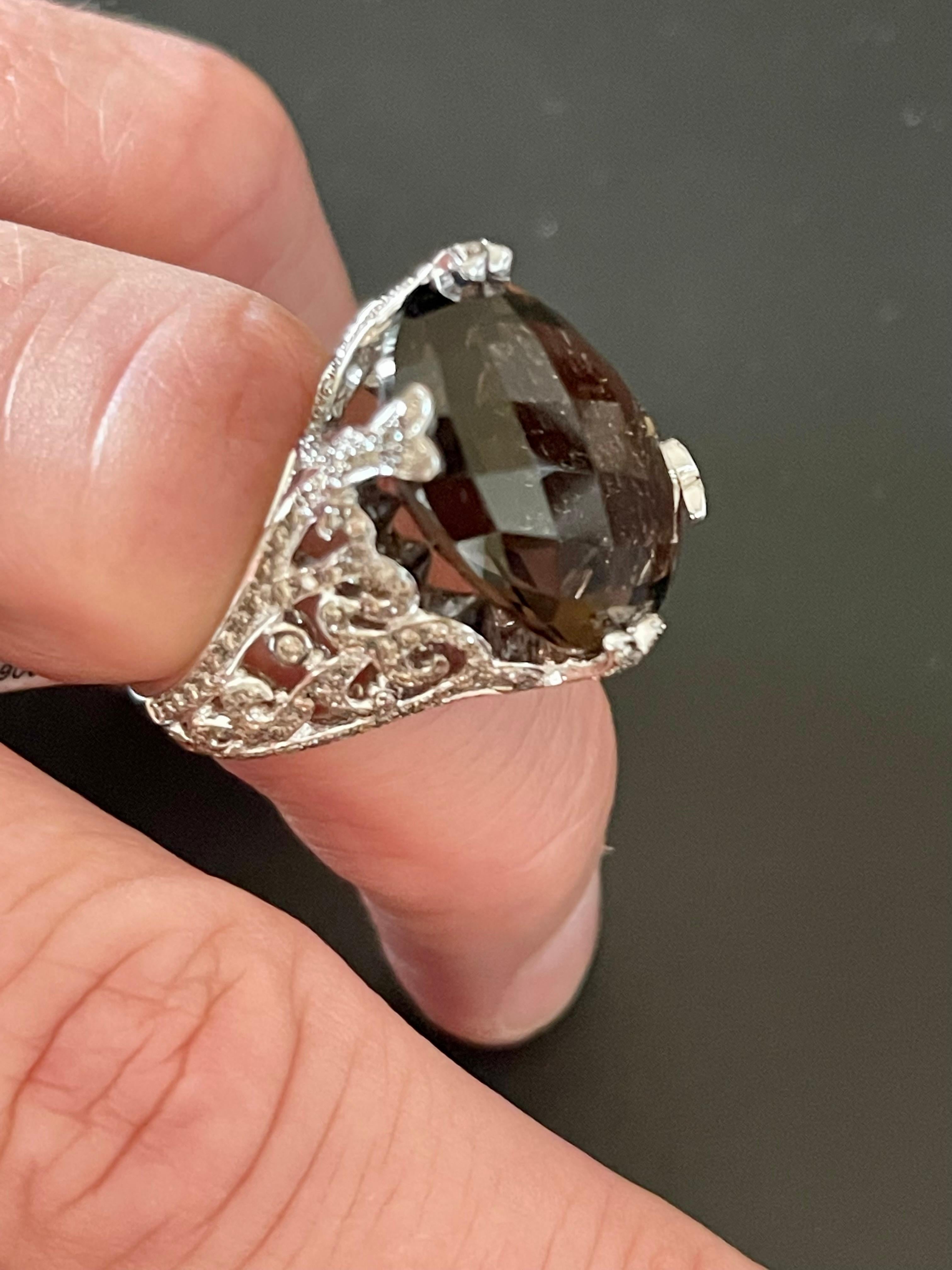 18 K white Gold Statement Ring featuring a fancy cut oval Smoky Quartz weighing 17.92 ct. The ring shoulders show beautiful ornaments reminiscing timeless byzantine craftmanship, set with 198 Champagne colored Diamonds weighing0.85 ct.  
This ring